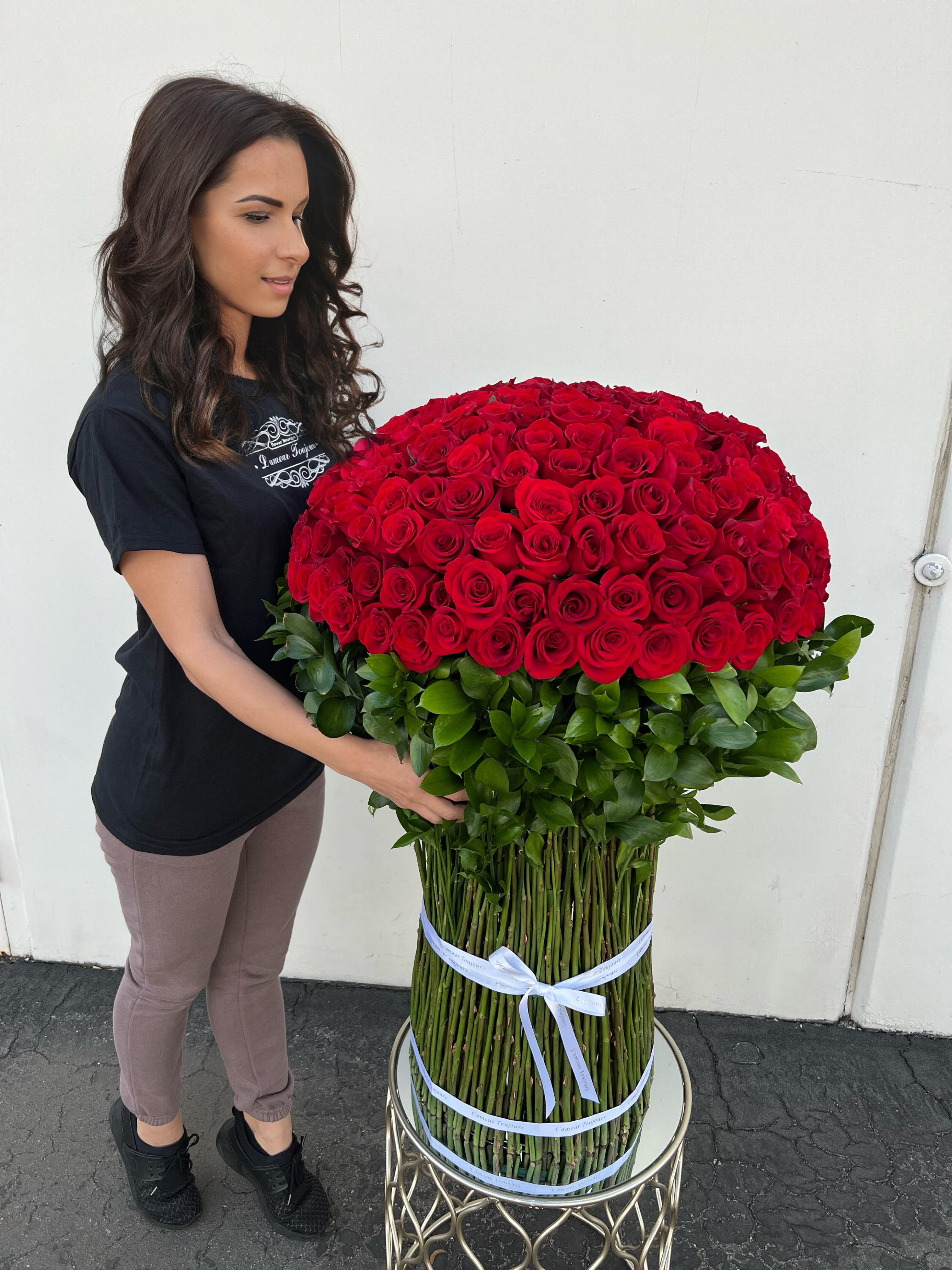 Woman holding a large bouquet of red roses with a green base