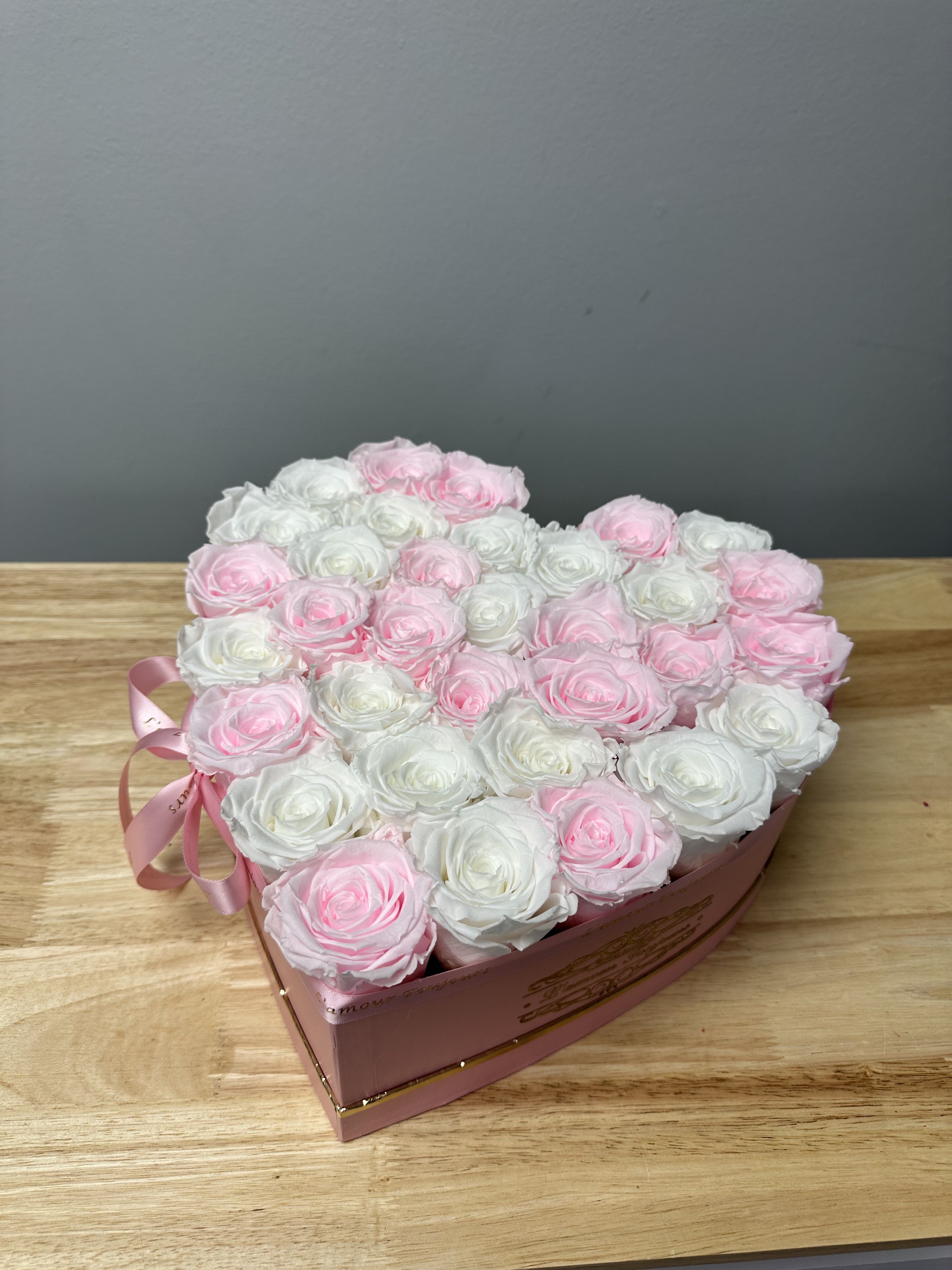 Heart-shaped box of pink and white roses with a ribbon bow