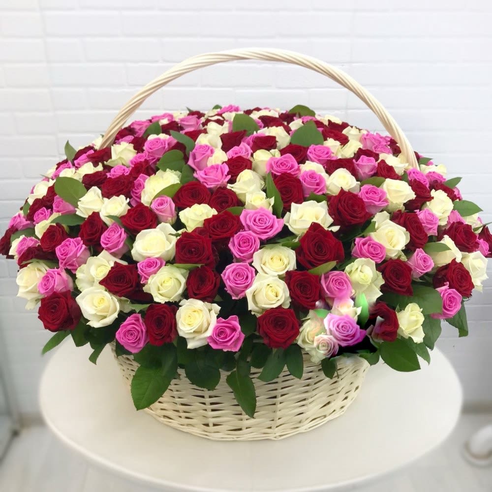 Large basket of red, white, and pink roses arranged densely in a white wicker basket