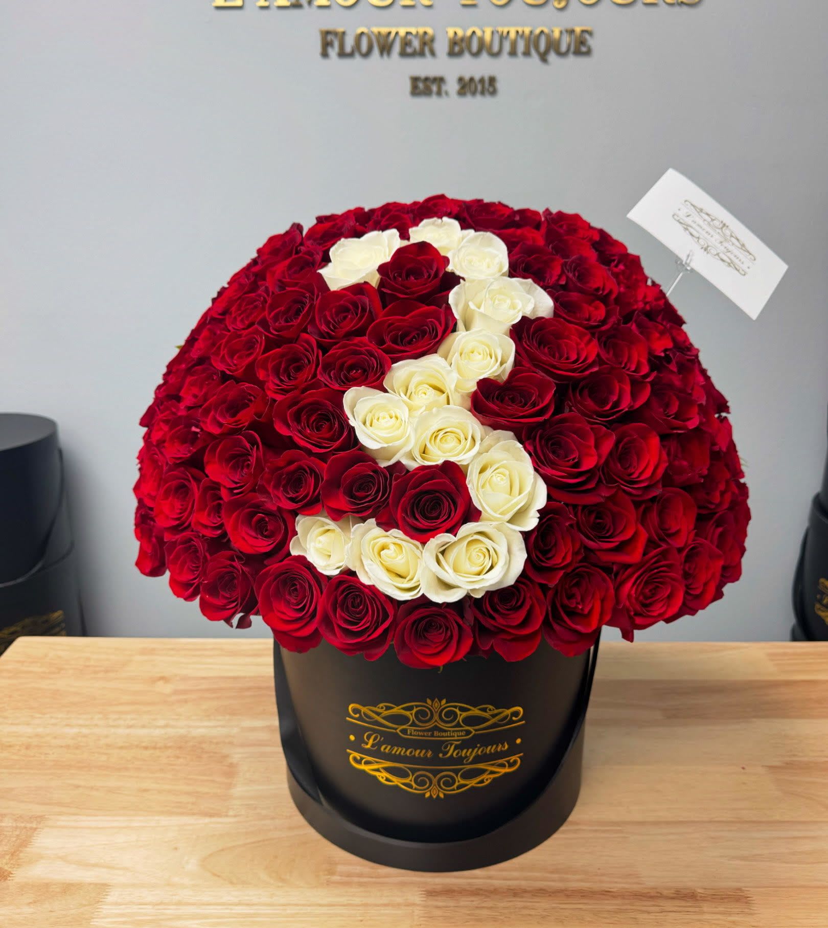 Large red and white rose arrangement in a black hatbox