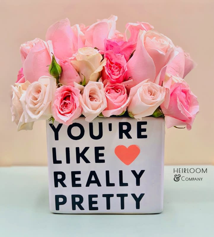 Pink and white roses in a square vase with a printed message