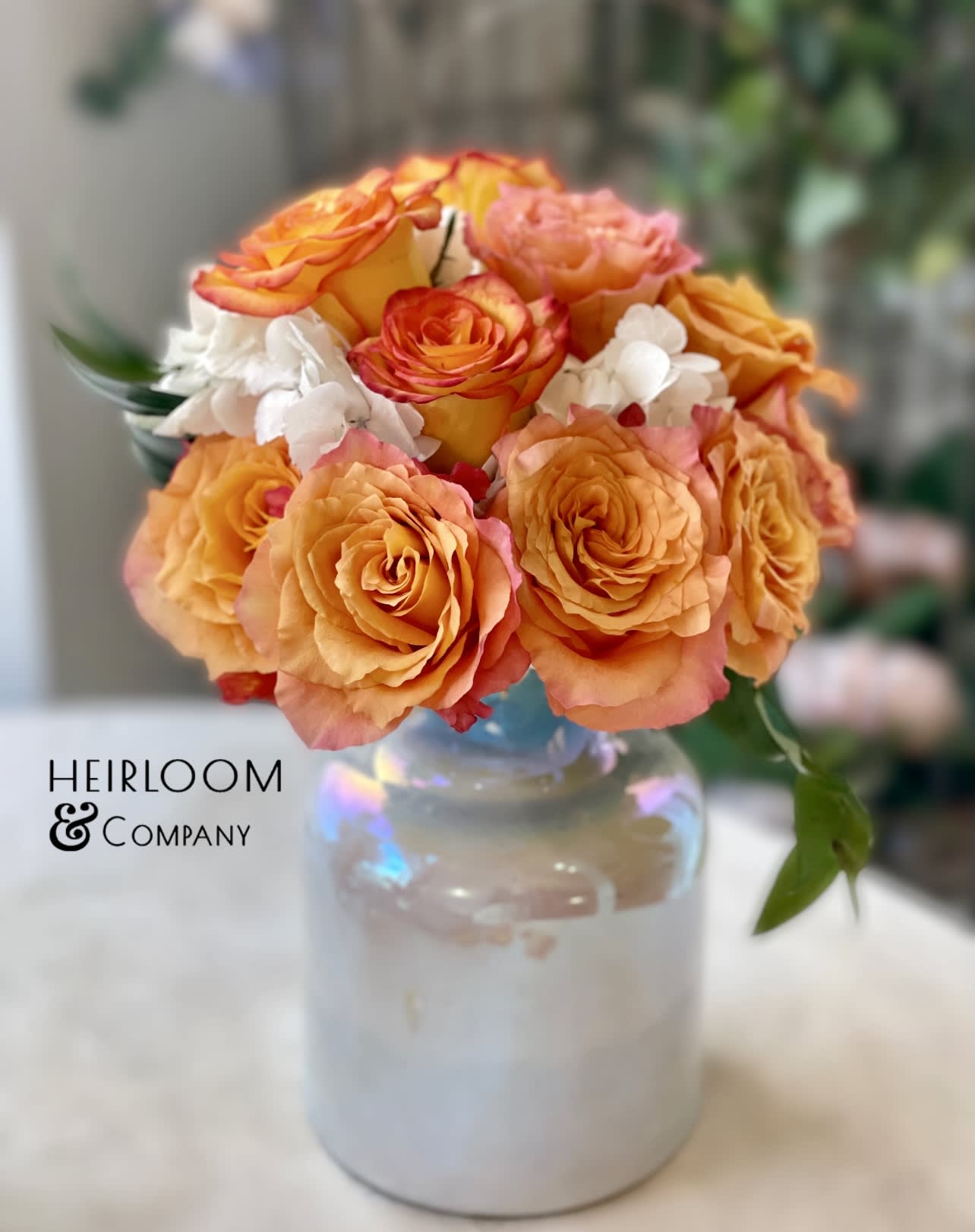 Orange and pink rose bouquet in a glass vase