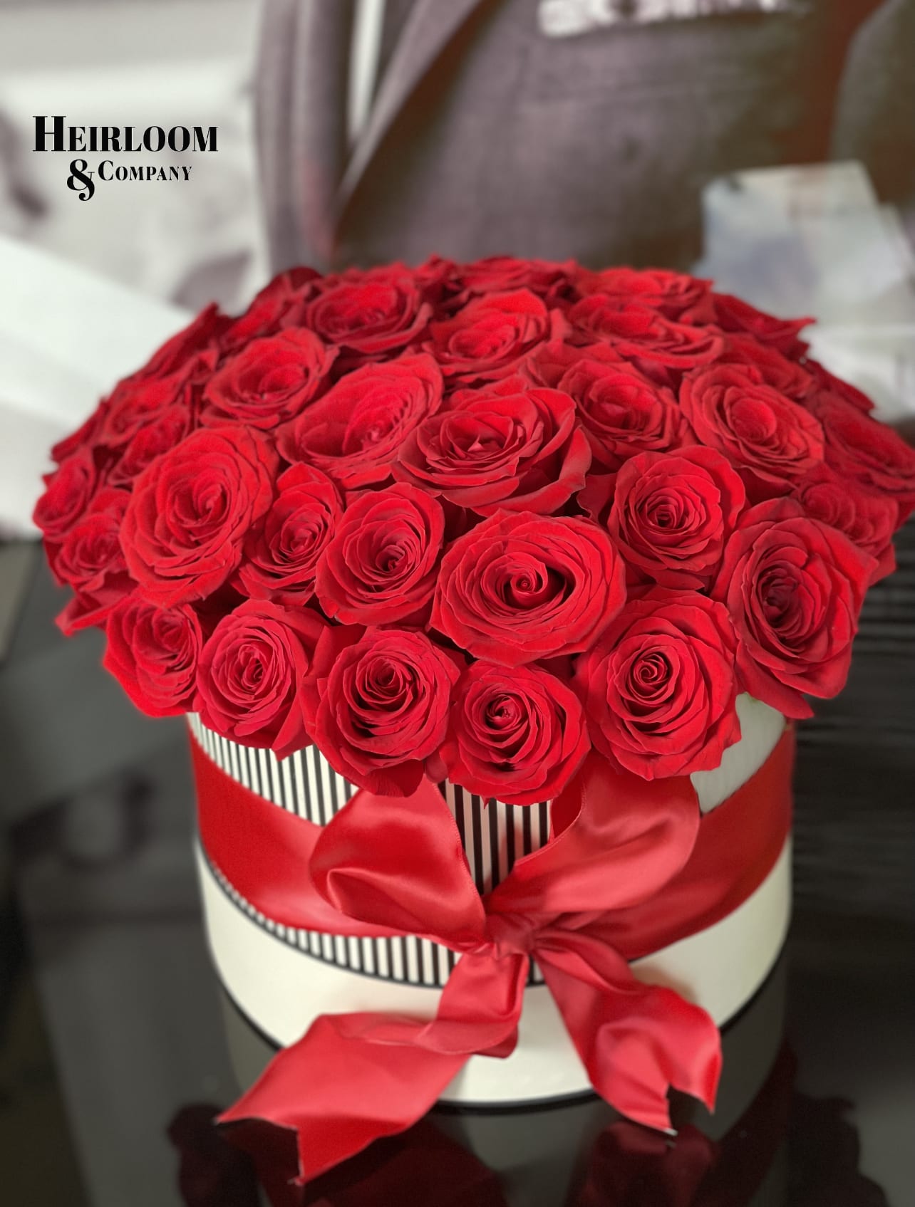 Red roses arranged in a round hat box with a red ribbon