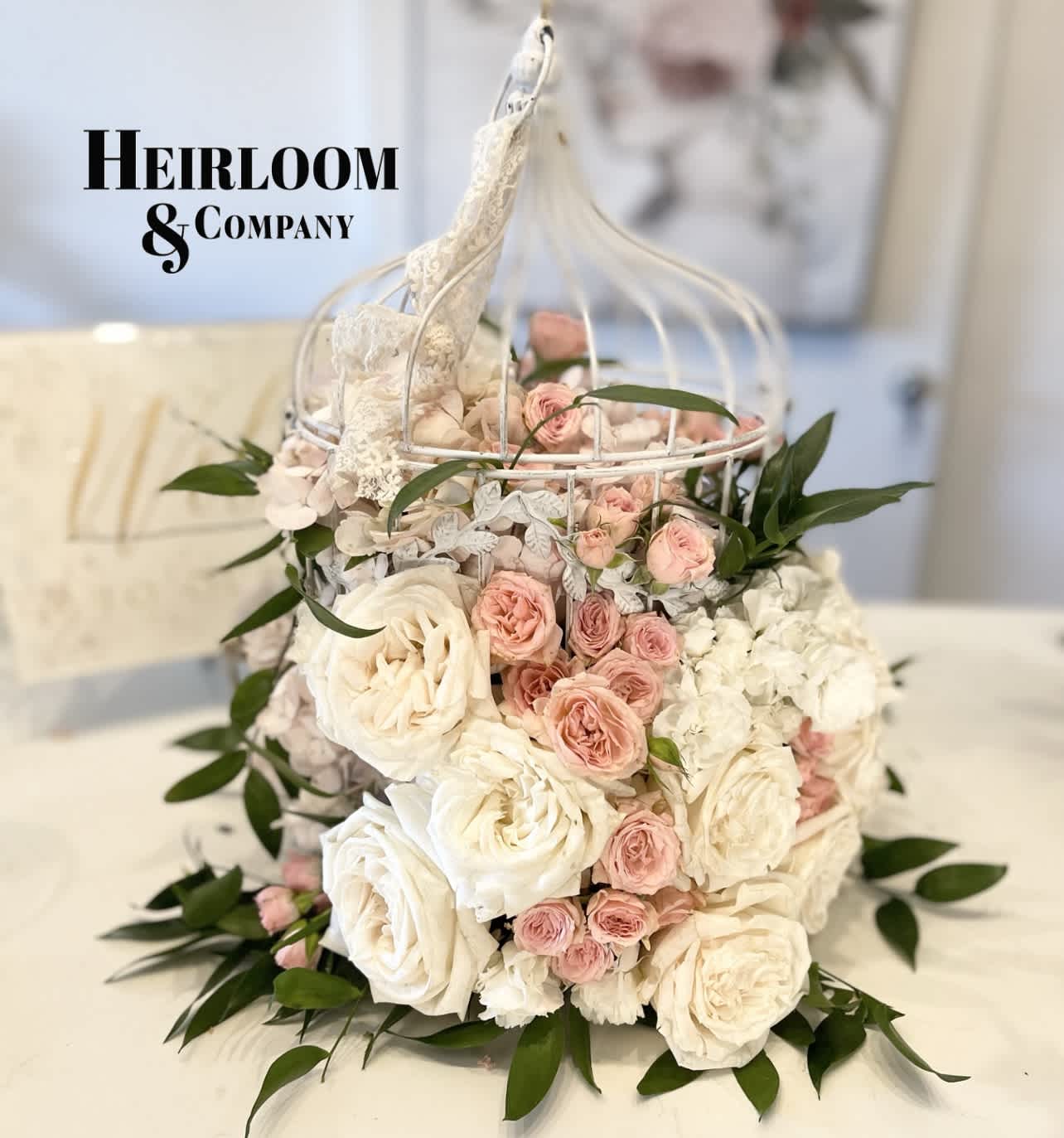 Pink and white roses arranged in a white birdcage