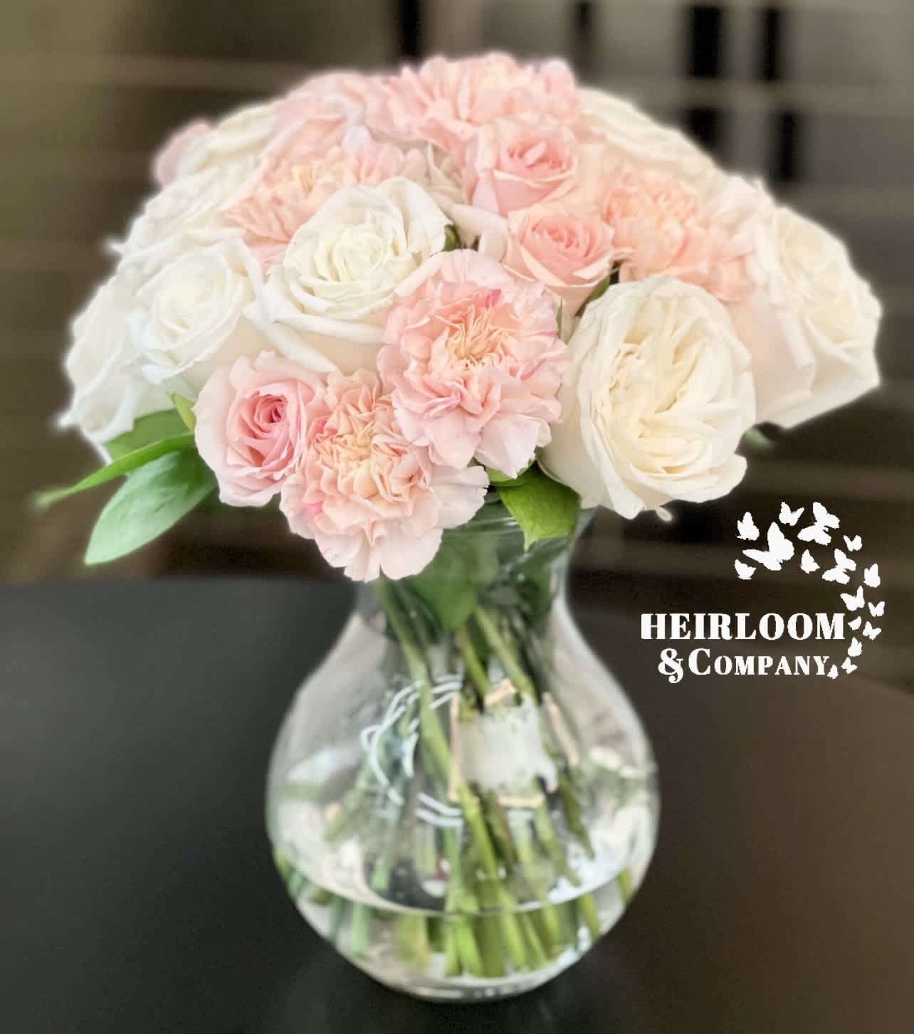 Pink and white roses with carnations in a clear glass vase