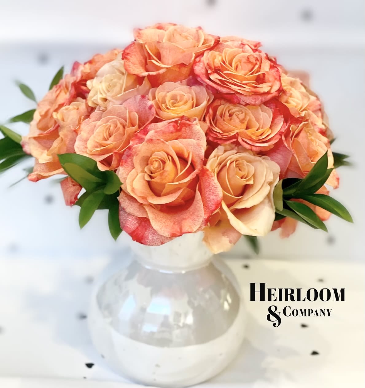 Peach and coral roses arranged in a clear glass vase