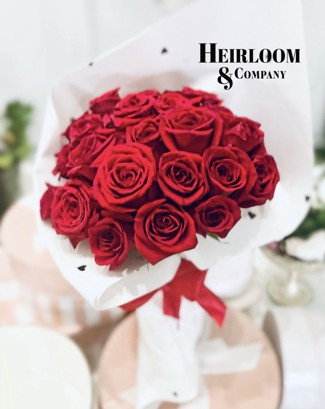 Paint The Roses Red - Deep, saturated red roses packed into a tight, rounded bouquet make a bold statement of love-perfect as an anniversary bouquet or a Valentine's Day surprise. Paint The Roses Red reads like a single, unmistakable message: romantic, polished, and impossible to ignore. The person you're thinking of will feel celebrated and adored the moment they lift the crisp white paper to reveal those velvety blooms.  This arrangement is composed entirely of vivid red roses gathered closely for a dense silhouette, wrapped in white paper (with tasteful black heart accents visible on some wraps) and finished with a wide red ribbon for a gift-ready look. The presentation is florist-polished rather than loose, keeping the bouquet neat and dramatic-ideal for classic romantic gestures or to say "I love you" on birthdays and thank-you moments.  Sized and styled to arrive ready to display or hand-deliver, this bouquet needs only a clean vase and fresh water to keep the roses at their best; remove any foliage below the waterline and change the water every other day for longer life. Whether marking a milestone or surprising someone just because, this is the kind of bouquet that makes the recipient feel truly seen and cherished.