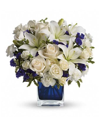 White lilies and roses arranged in a blue glass vase
