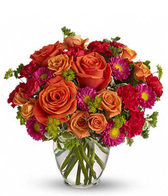 Orange roses and pink daisies in a clear glass vase