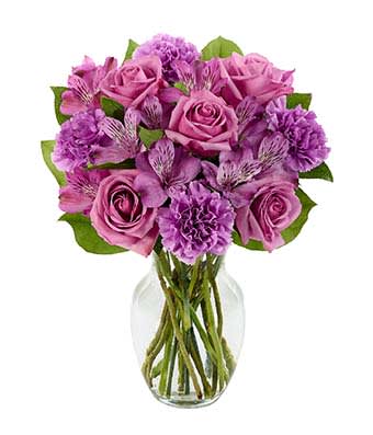 Purple roses and carnations in a clear glass vase