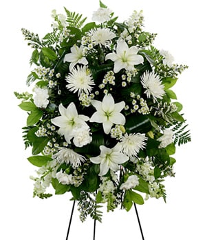White floral standing spray on an easel with lilies and chrysanthemums