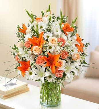 Sincerest Sorrow - Peach, Orange and White - Product ID: 95426   Express your sorrow with a memorable tribute: our bright and beautiful arrangement of lilies, roses, gladiolas, stock, daisy poms and more. Awash in soothing shades of peach, orange and white, it's hand-crafted by our florists in a classic vase for the home or service. Lush peach, orange and white arrangement of roses, lilies, gladiolas, stock, daisy poms, carnations and monte casino, accented with variegated pittosporum, salal, myrtle and bear grass Hand-designed by our select florists in a classic glass cylinder vase; vase measures 8"H Can be sent to the home of friends, family members or business associates, or to the funeral service Large arrangement measures approximately 24"H x 22"L Medium arrangement measures approximately 22"H x 20"L Small arrangement measures approximately 20"H x 18"L Our florists hand-design each arrangement, so colors, varieties, and container may vary due to local availability Lilies may arrive in bud form and will open to full beauty over the next 2-3 days