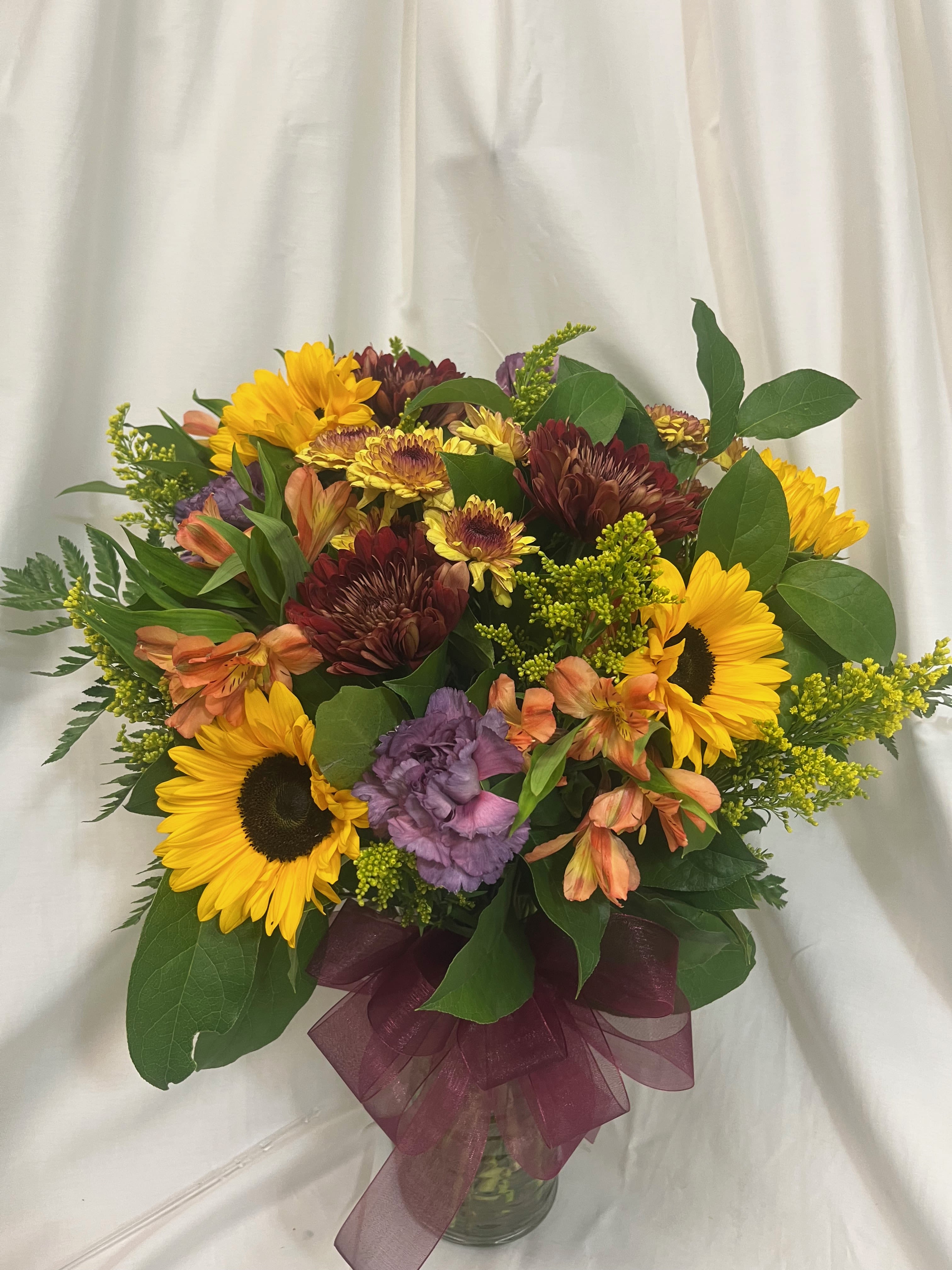 Mixed bouquet with sunflowers, chrysanthemums, and alstroemeria in a glass vase