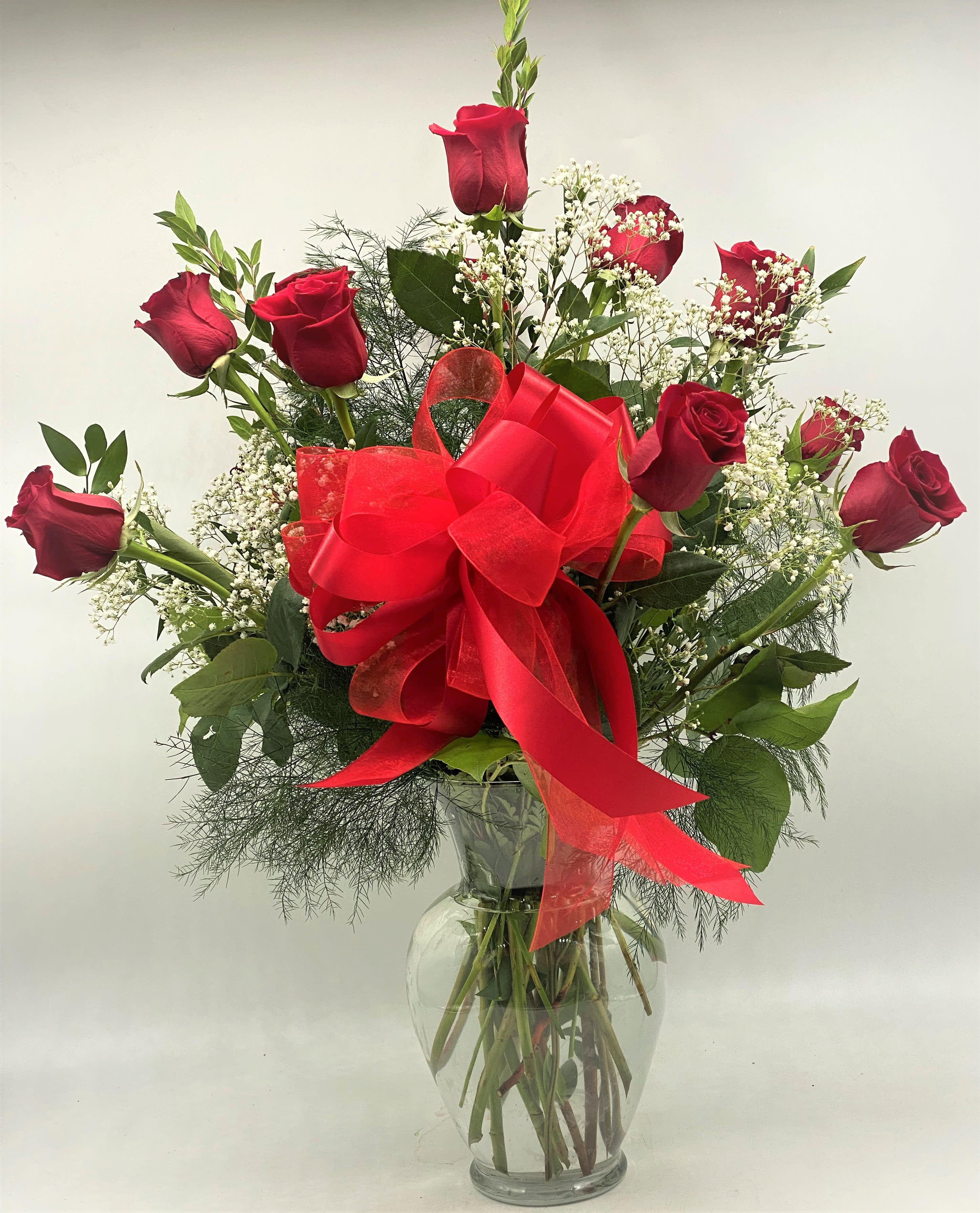 Red roses in a clear glass vase with a large red bow