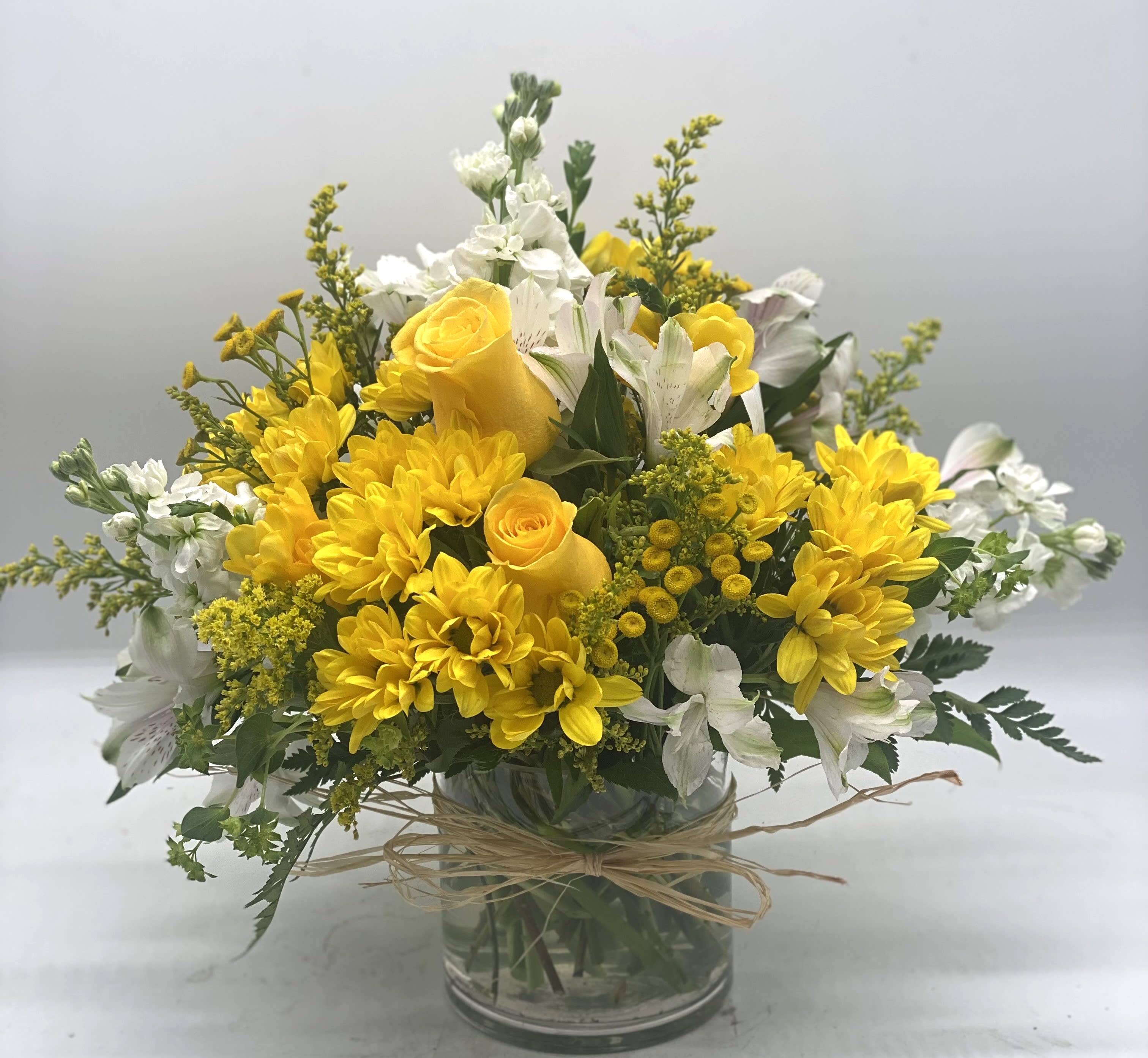 Fall Sunshine Bouquet - A beautiful and bright mix of yellows and whites designed in a cylinder vase and finished off with a raffia bow! Great way to brighten someone's day!