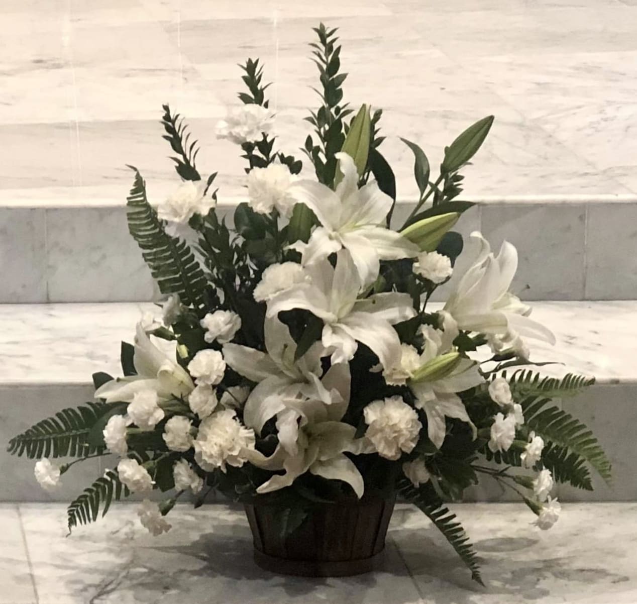 Peaceful Basket - Whether you send this beautiful arrangement to the family home or to the service, all will appreciate its elegance and grace. The contrast of brilliant white blossoms and dazzling greenery create a wonderfully calm and dignified setting.