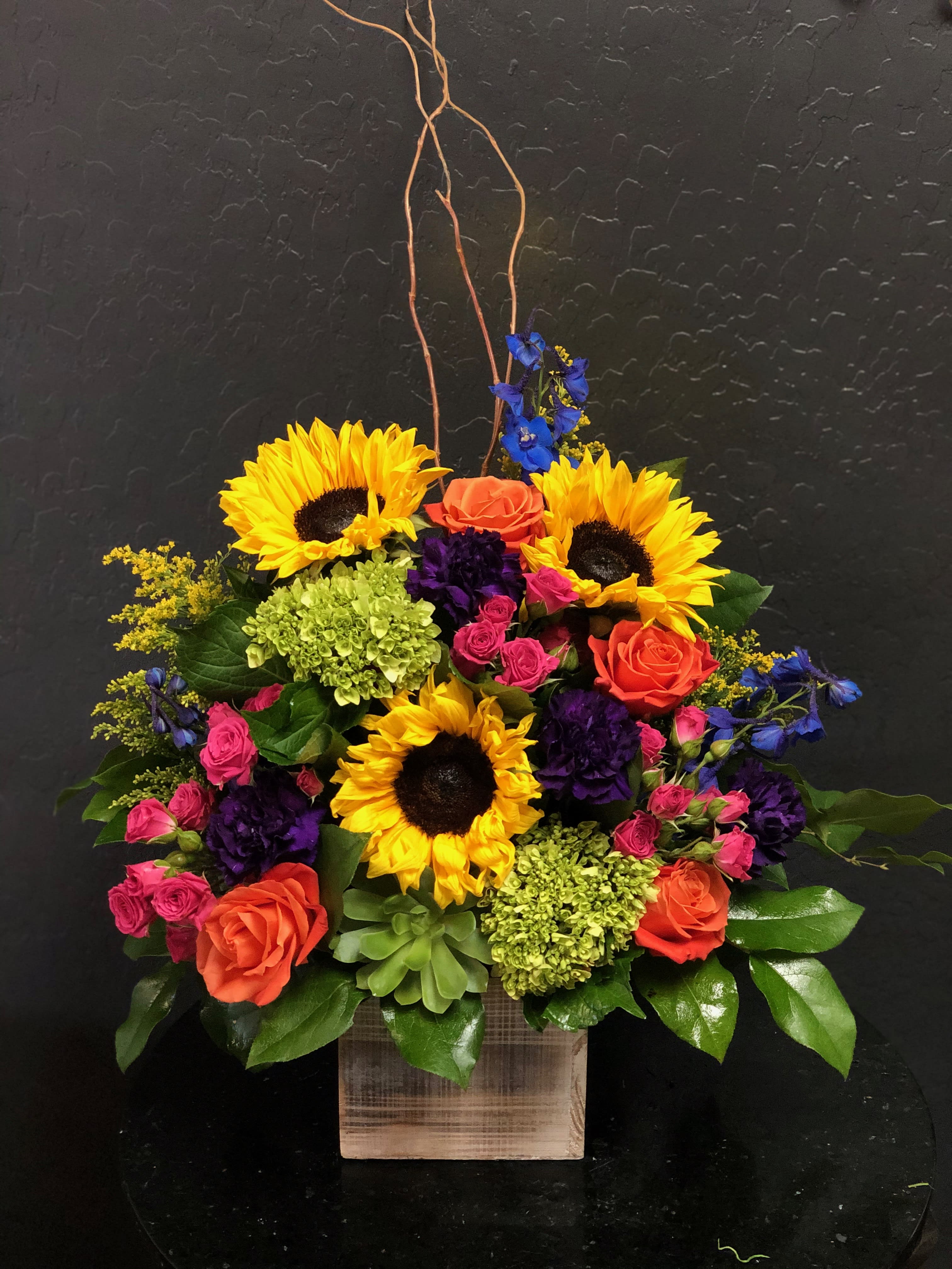 Colorful flower arrangement with sunflowers, roses, and hydrangeas in a wooden box