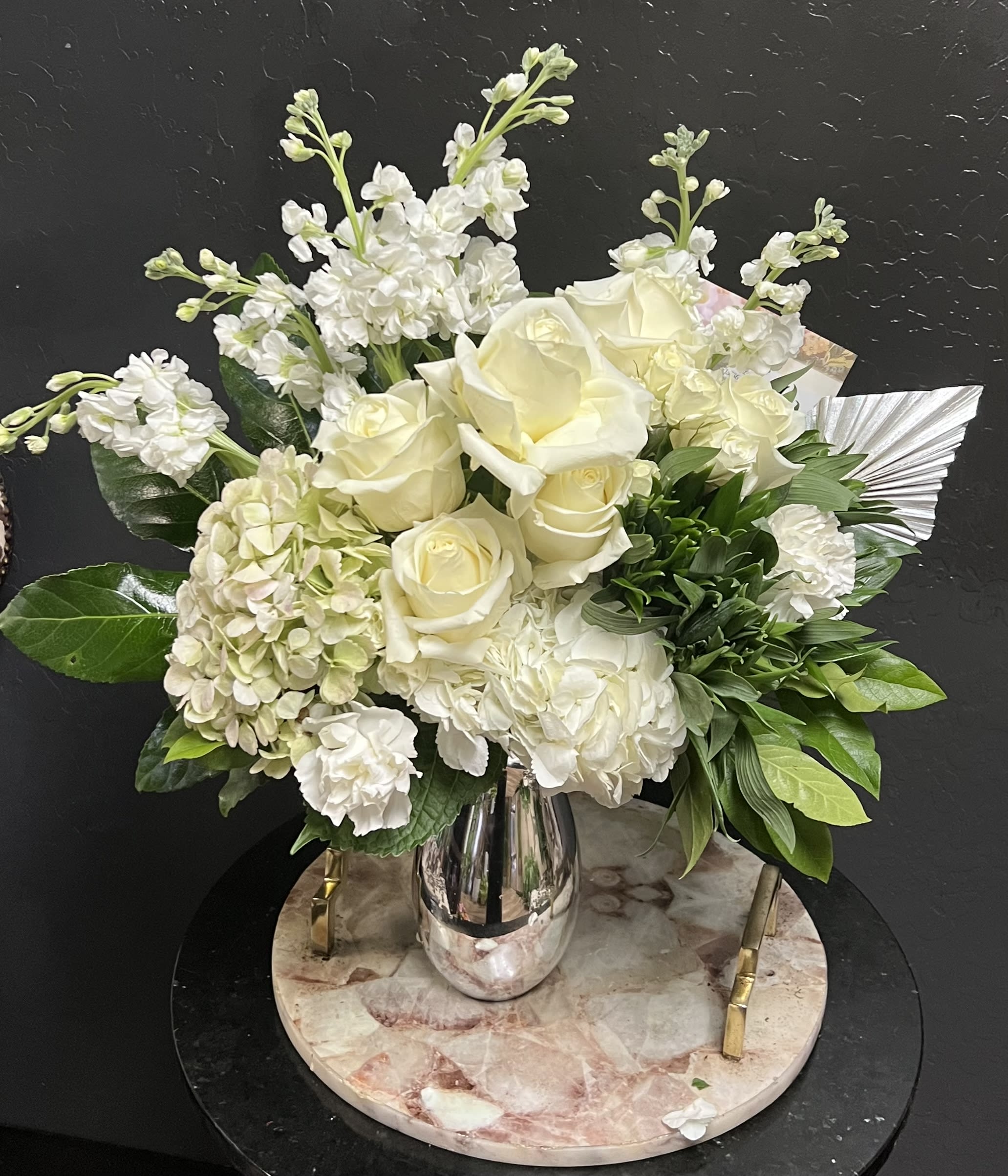 White roses and hydrangeas arranged in a silver vase