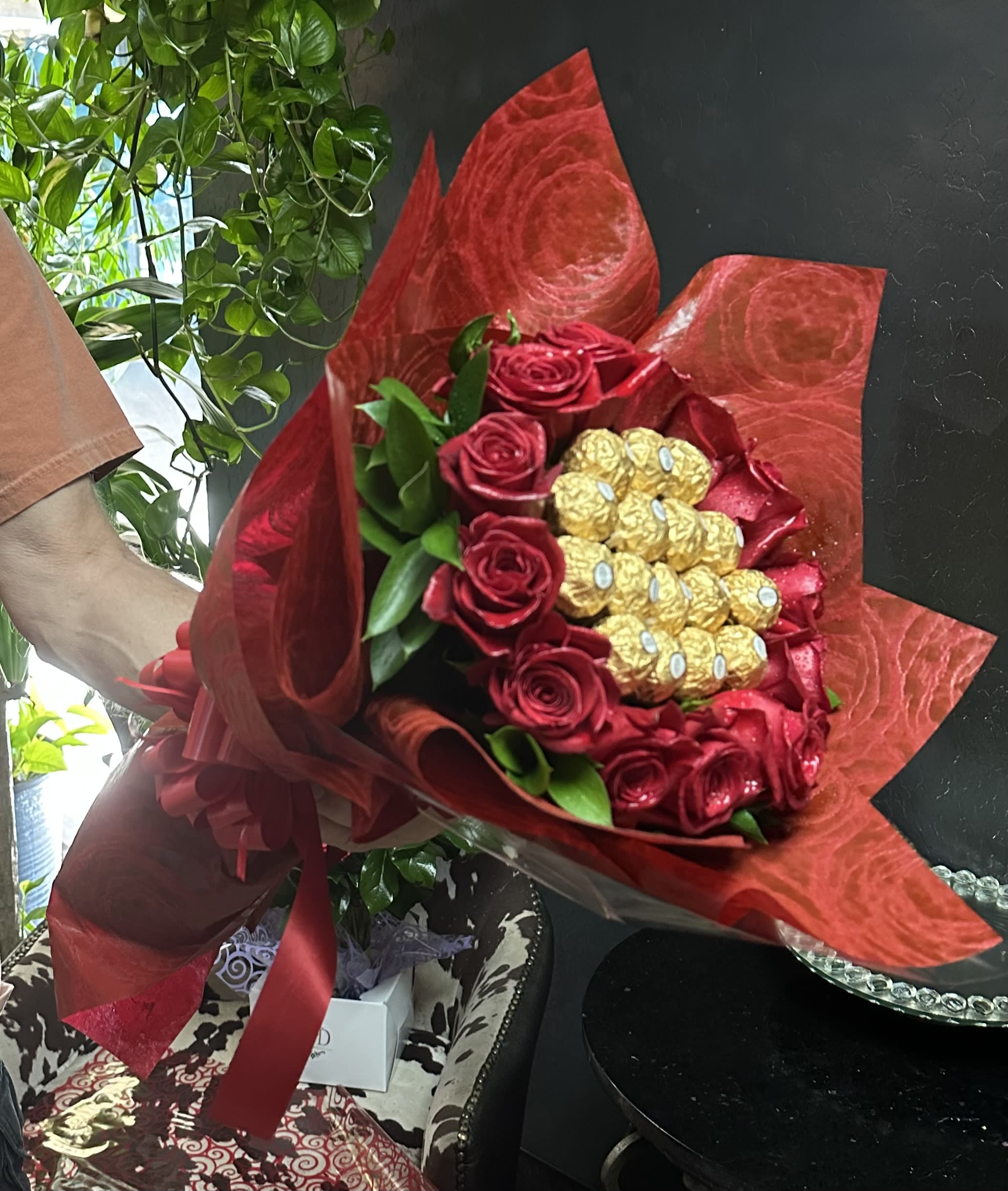 Bouquet of red roses with gold-wrapped chocolates in red wrapping