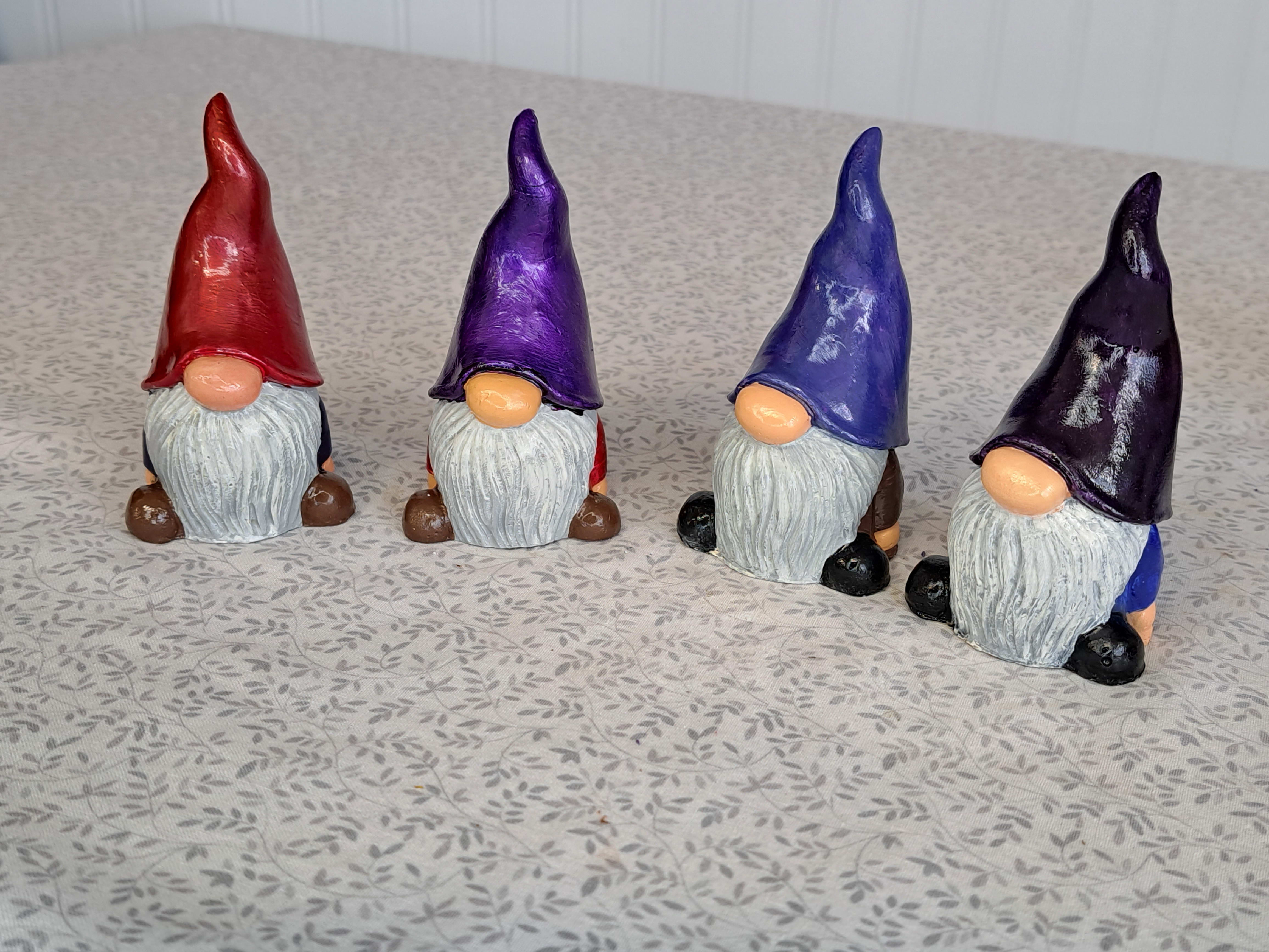 Four painted gnome figurines with tall hats on a patterned surface