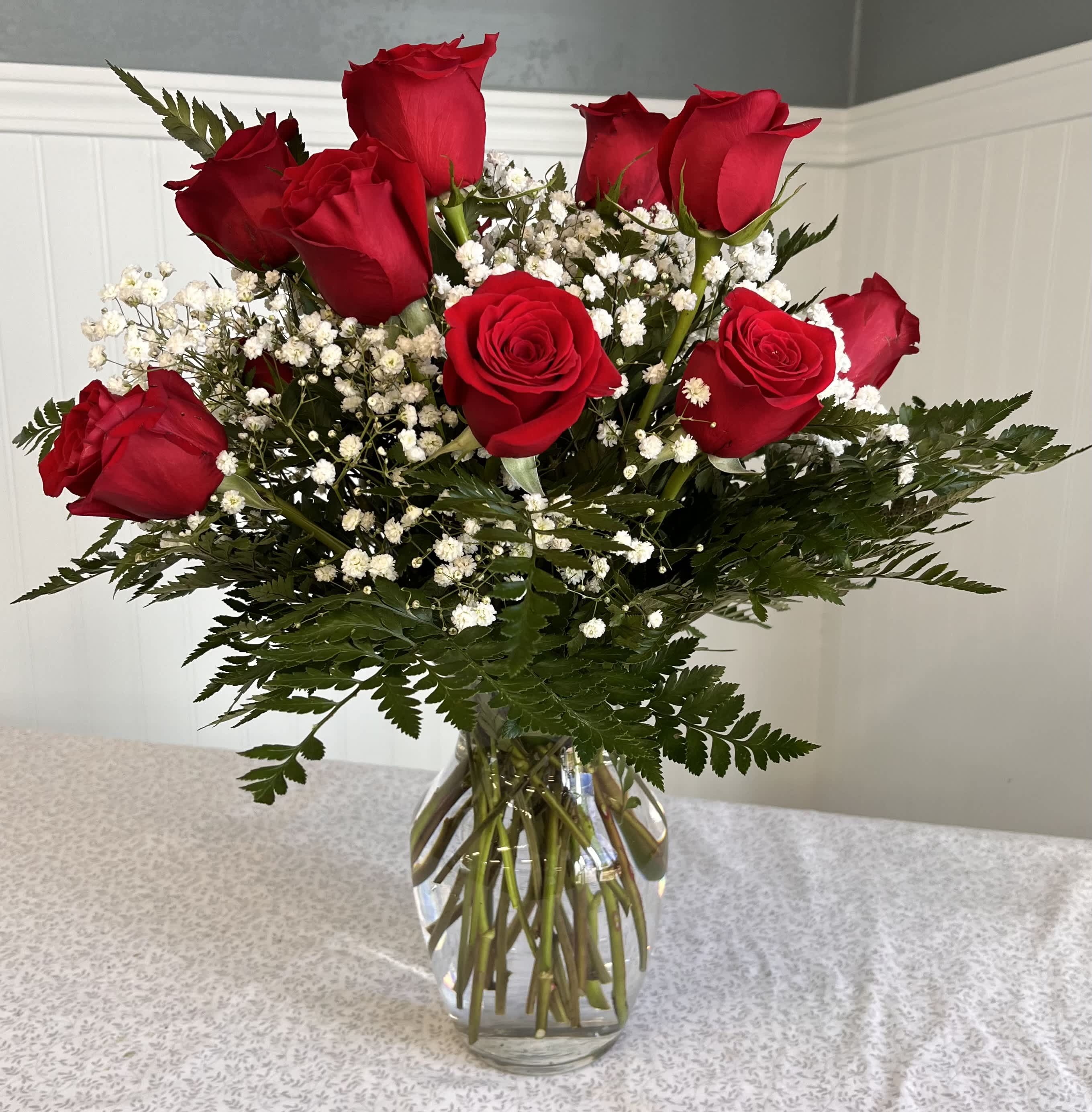 Red roses with baby's breath in a clear glass vase