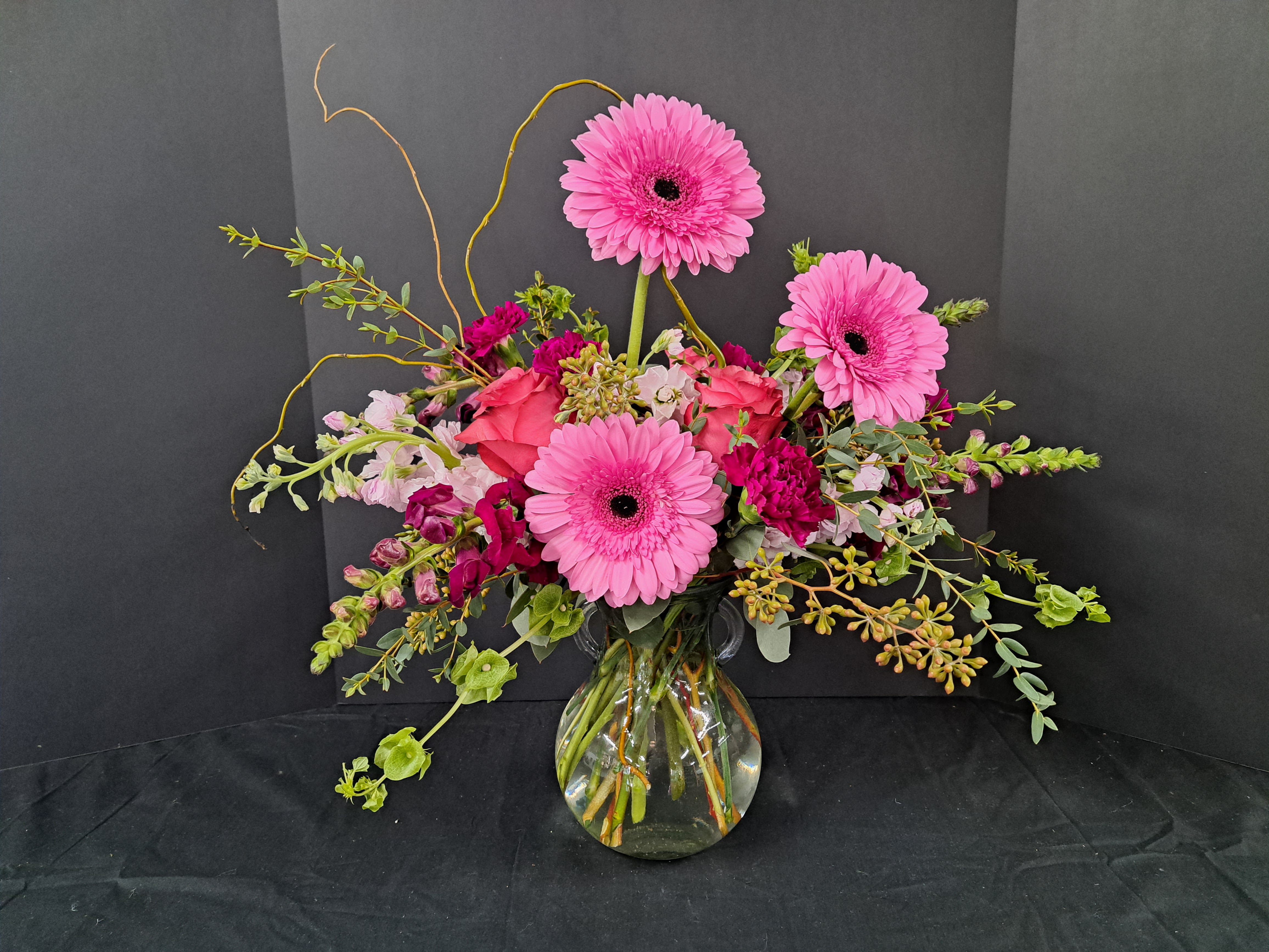 Pink gerbera daisies and mixed blooms in a clear glass vase
