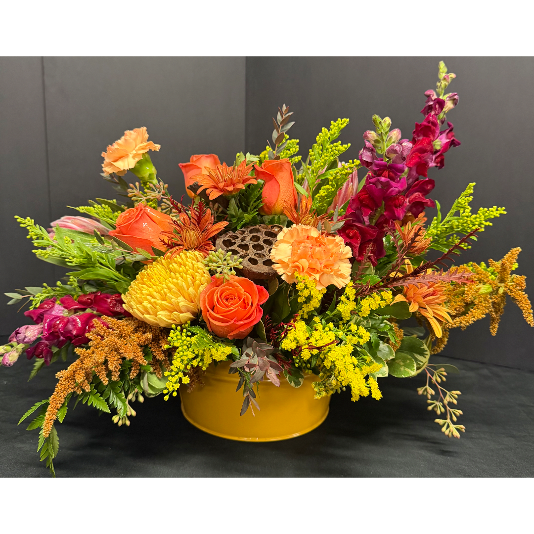 Bright mixed flower arrangement in a yellow container