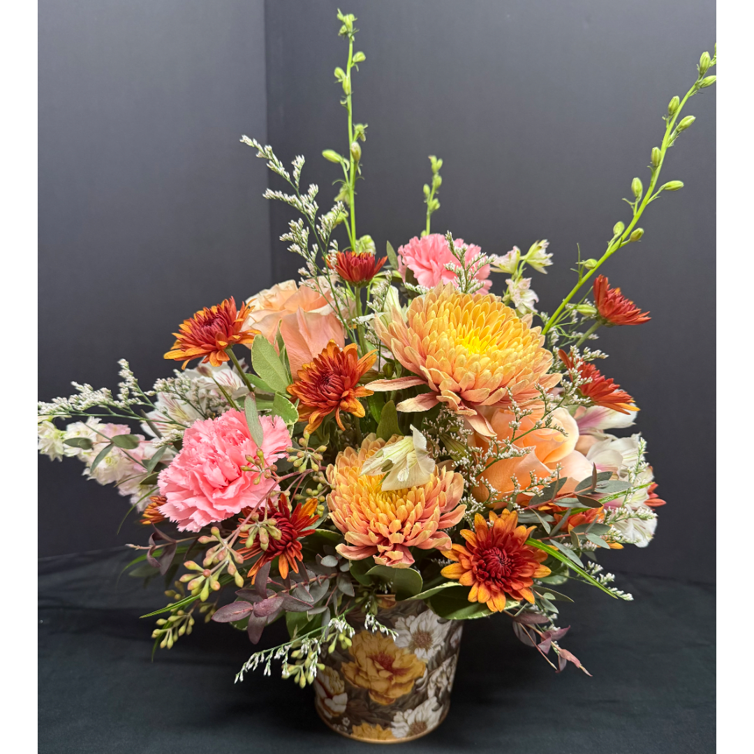 Mixed floral arrangement in a patterned container with orange, pink, and white blooms