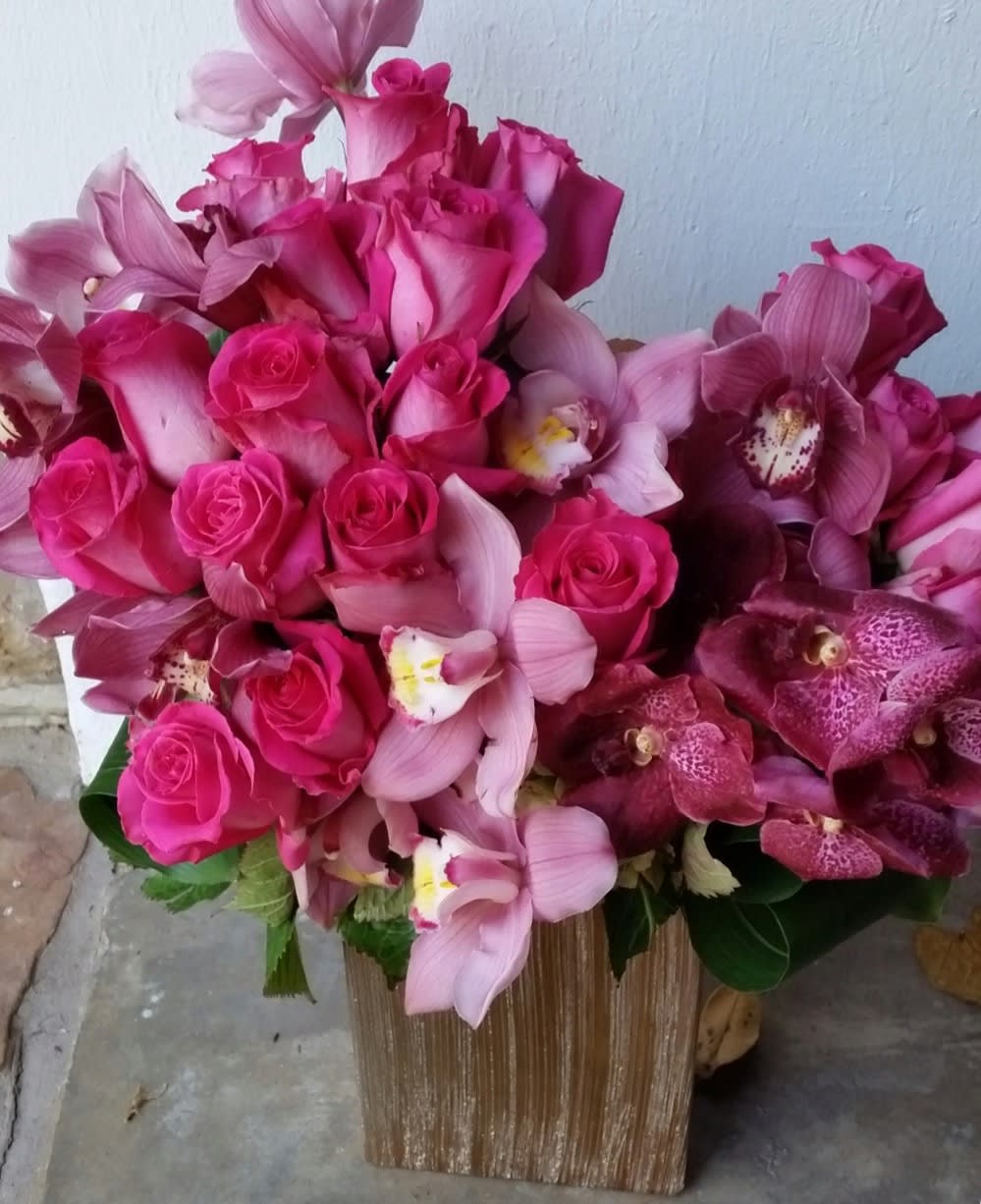 Pink roses and orchids arranged in a gold vase