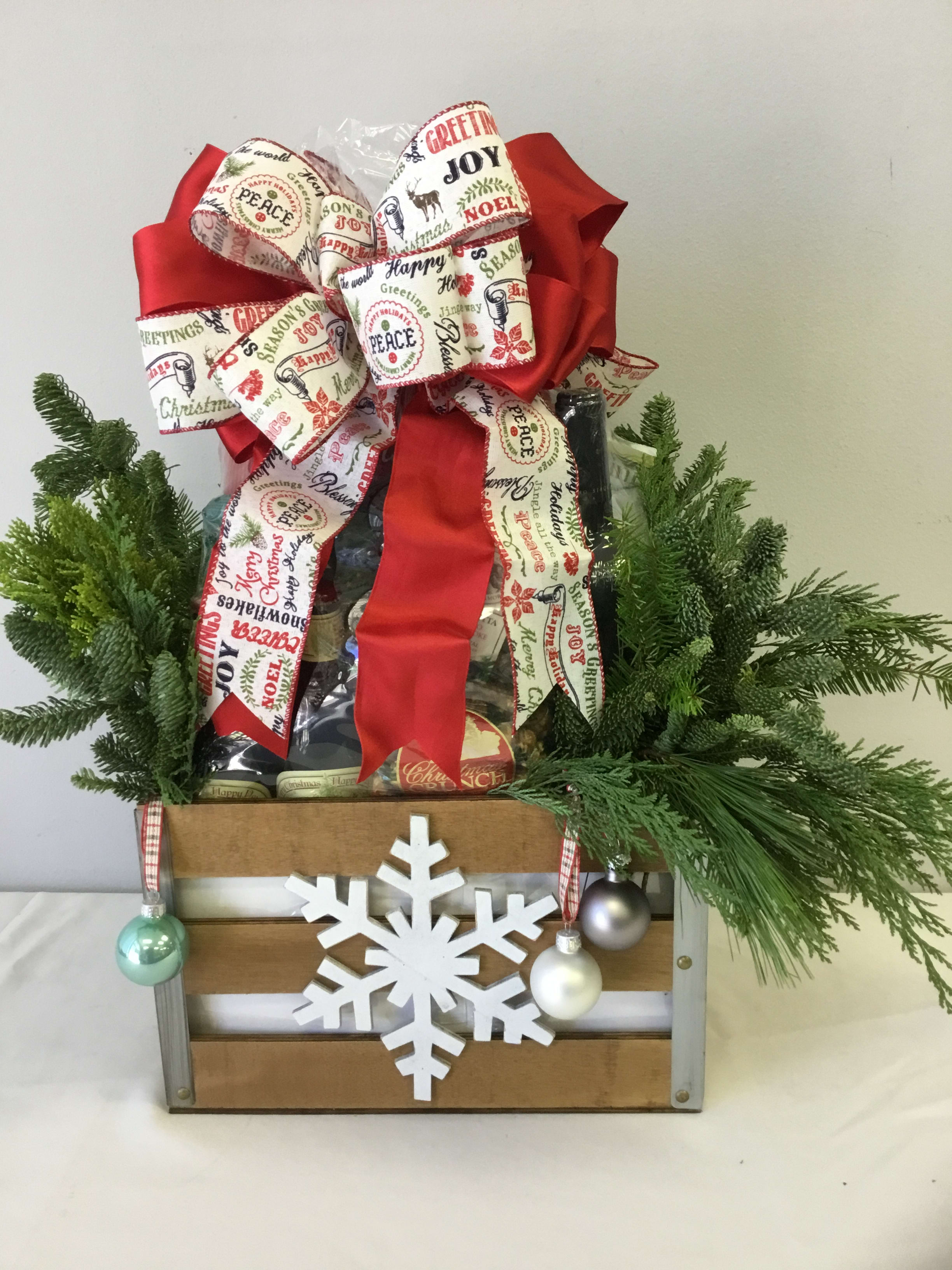 Christmas gift basket with a large red bow, evergreen branches, and a snowflake ornament