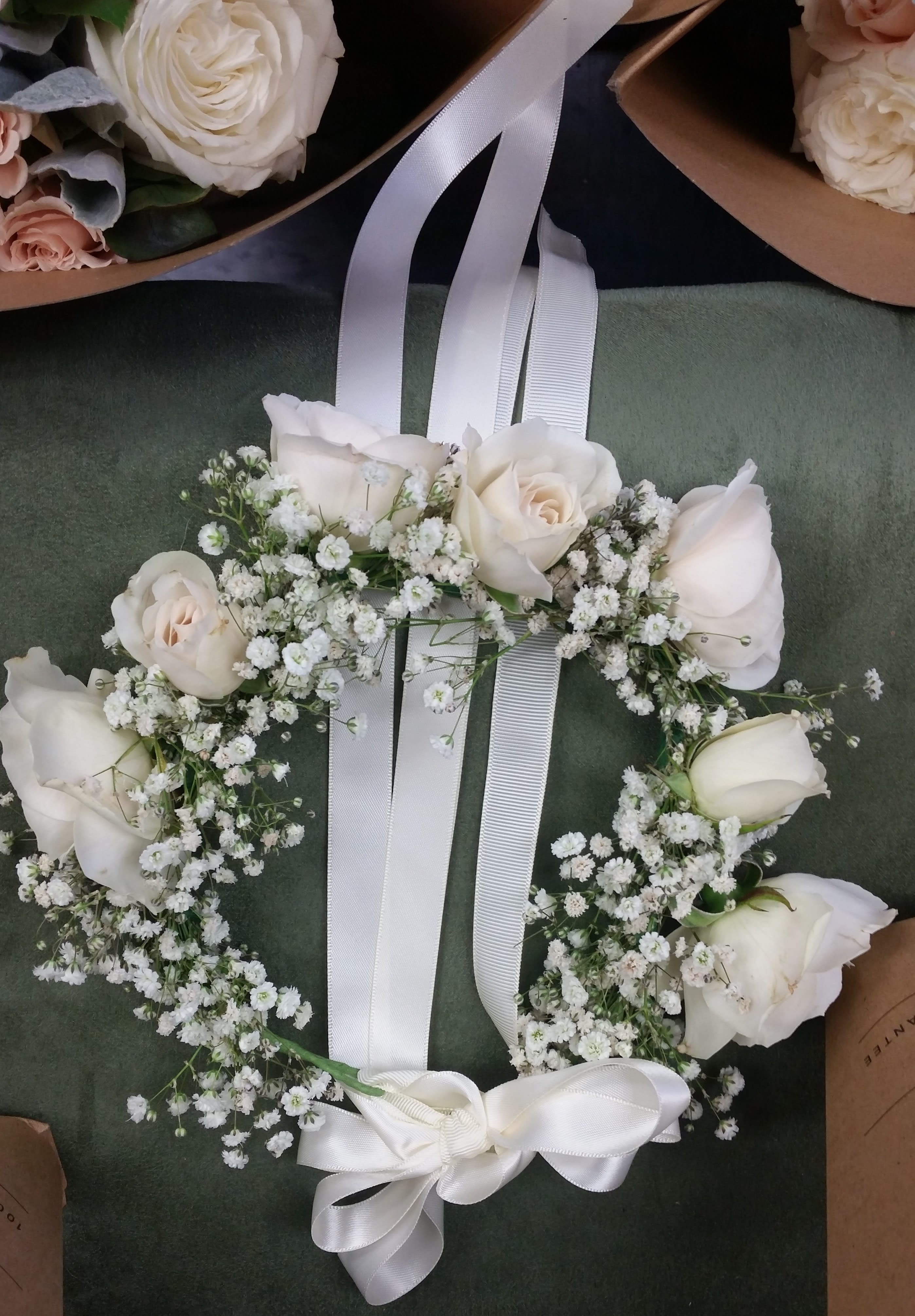 White rose floral wreath with baby's breath and a white ribbon bow