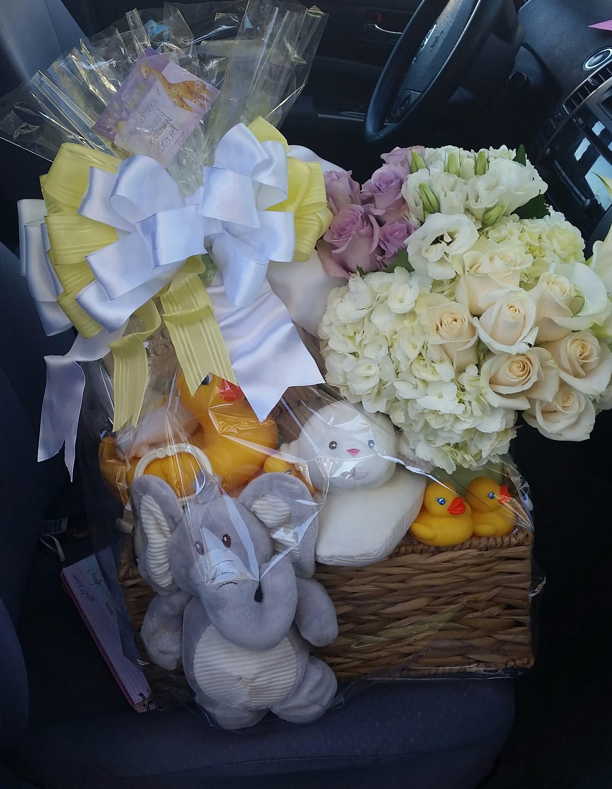 Basket of white and lavender flowers with plush toys and ribbon bows