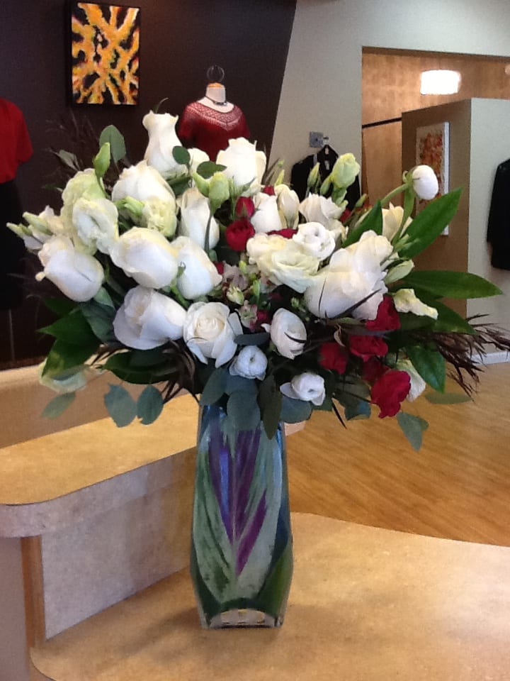 Large bouquet of white and red flowers in a tall glass vase