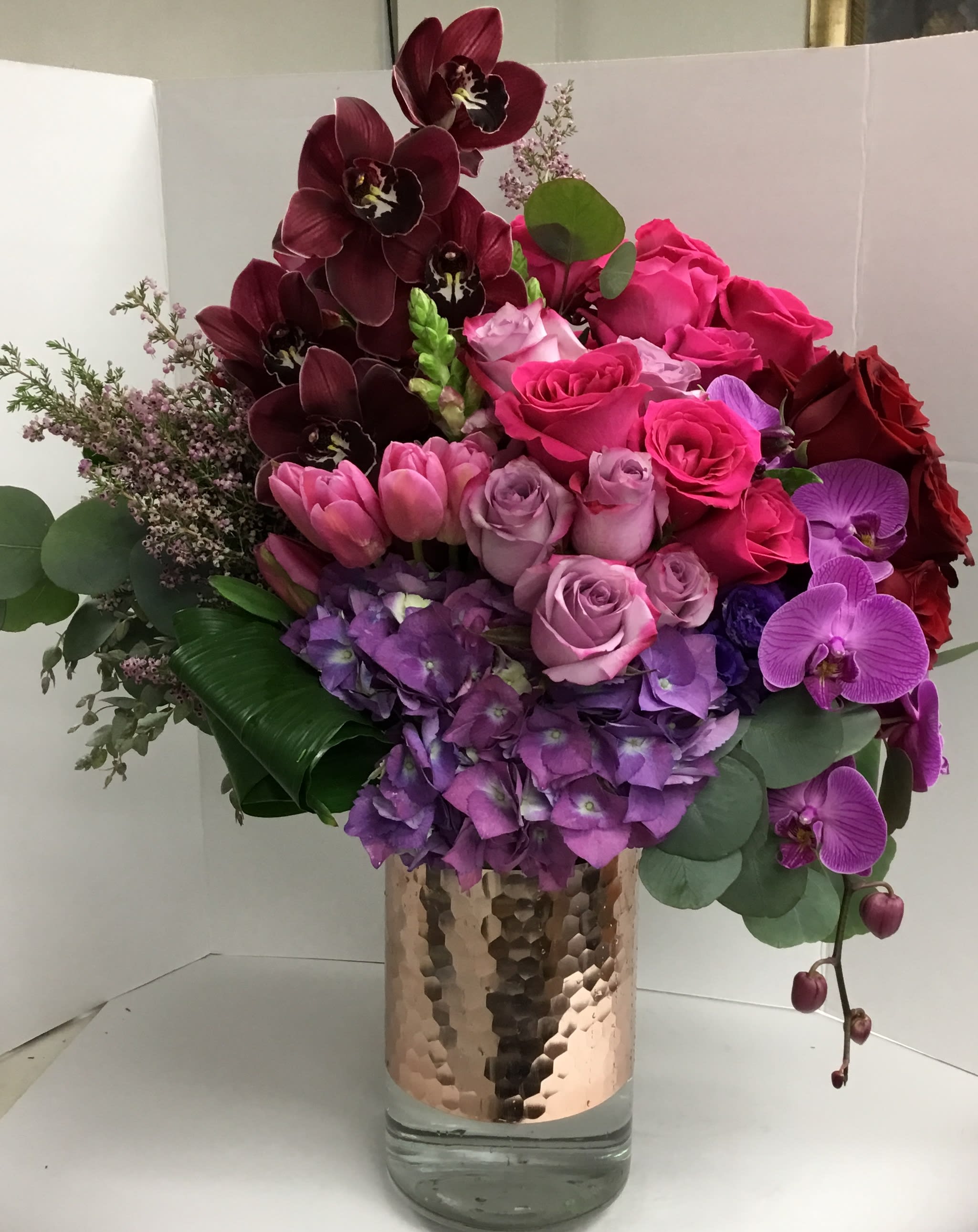 Bouquet of pink, purple, and burgundy flowers in a glass vase