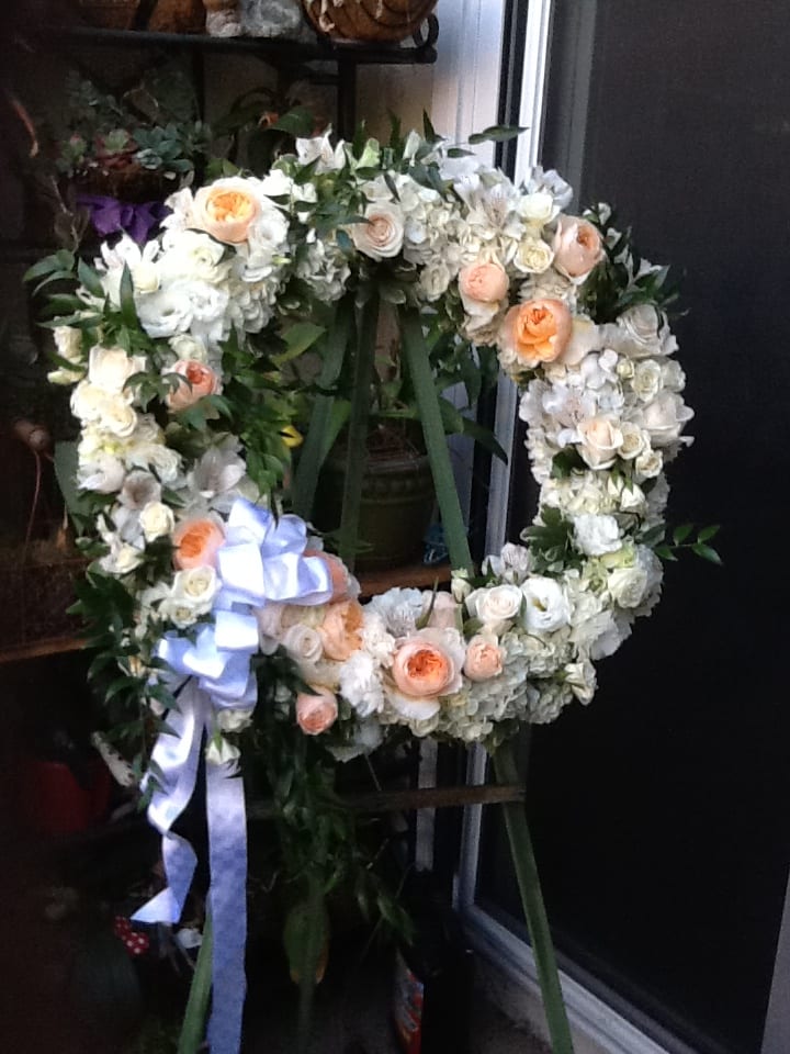 Heart-shaped floral wreath with white and peach roses and a lavender ribbon