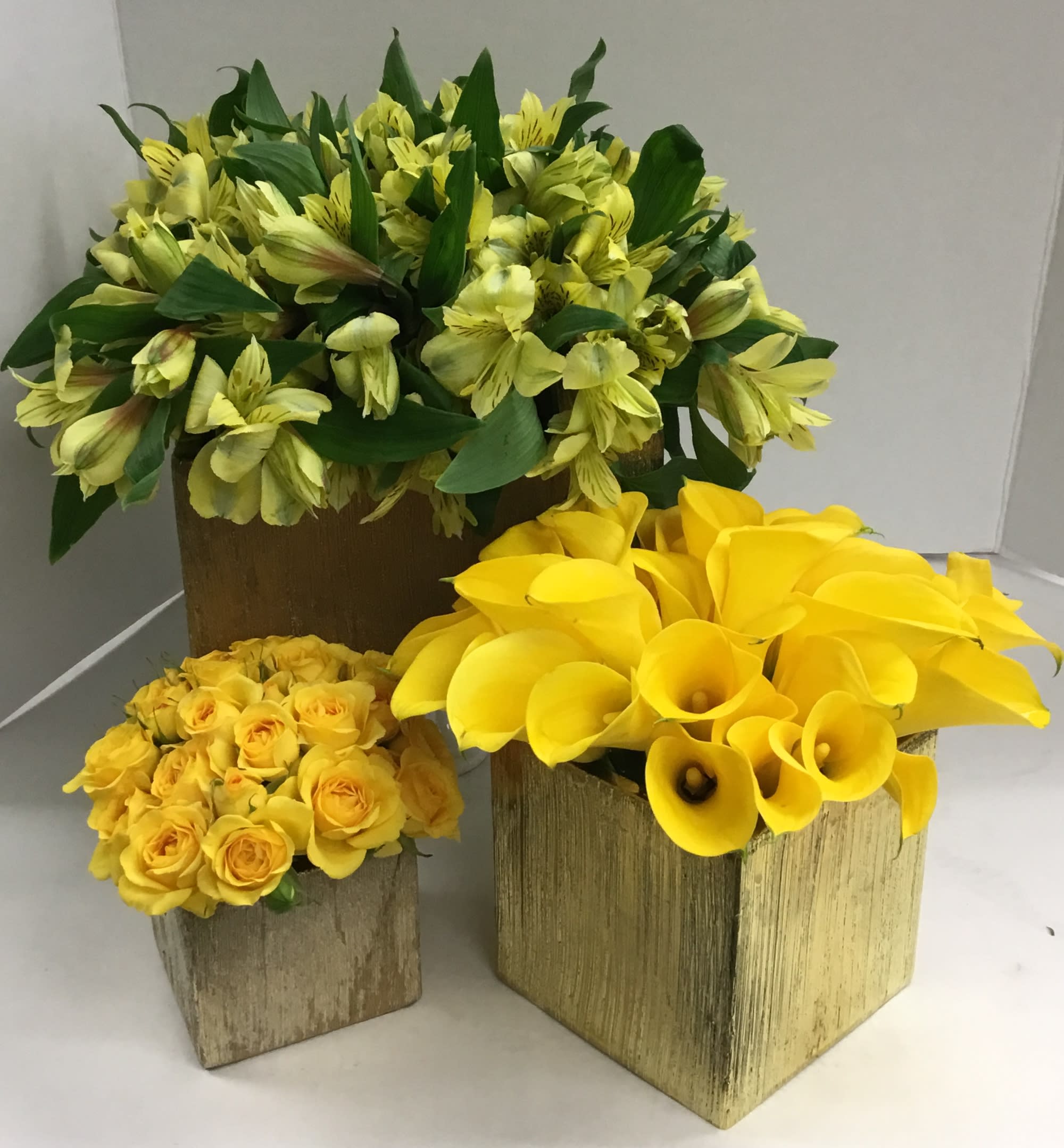 Three yellow floral arrangements in wooden boxes