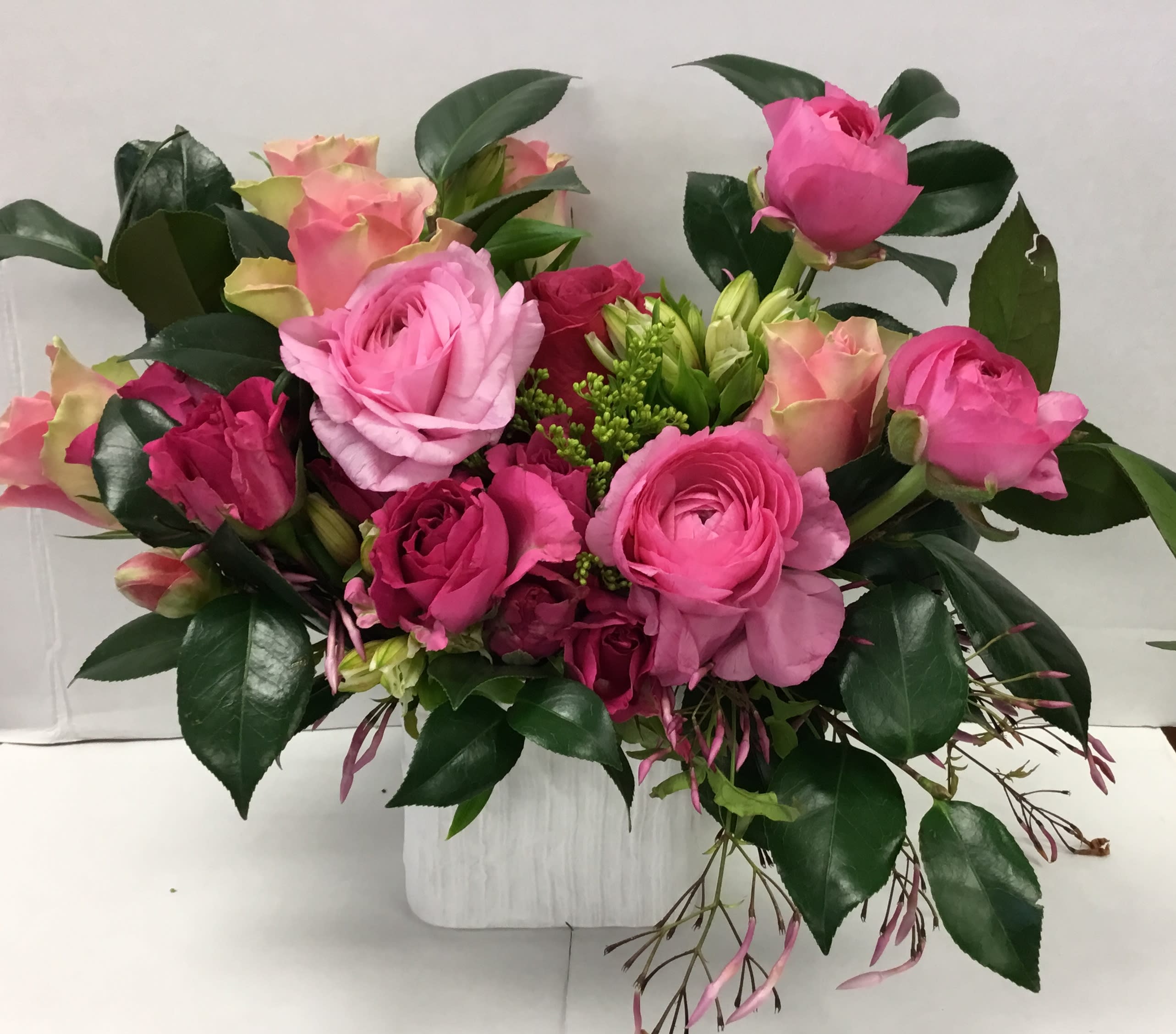Pink and peach rose bouquet in a white container