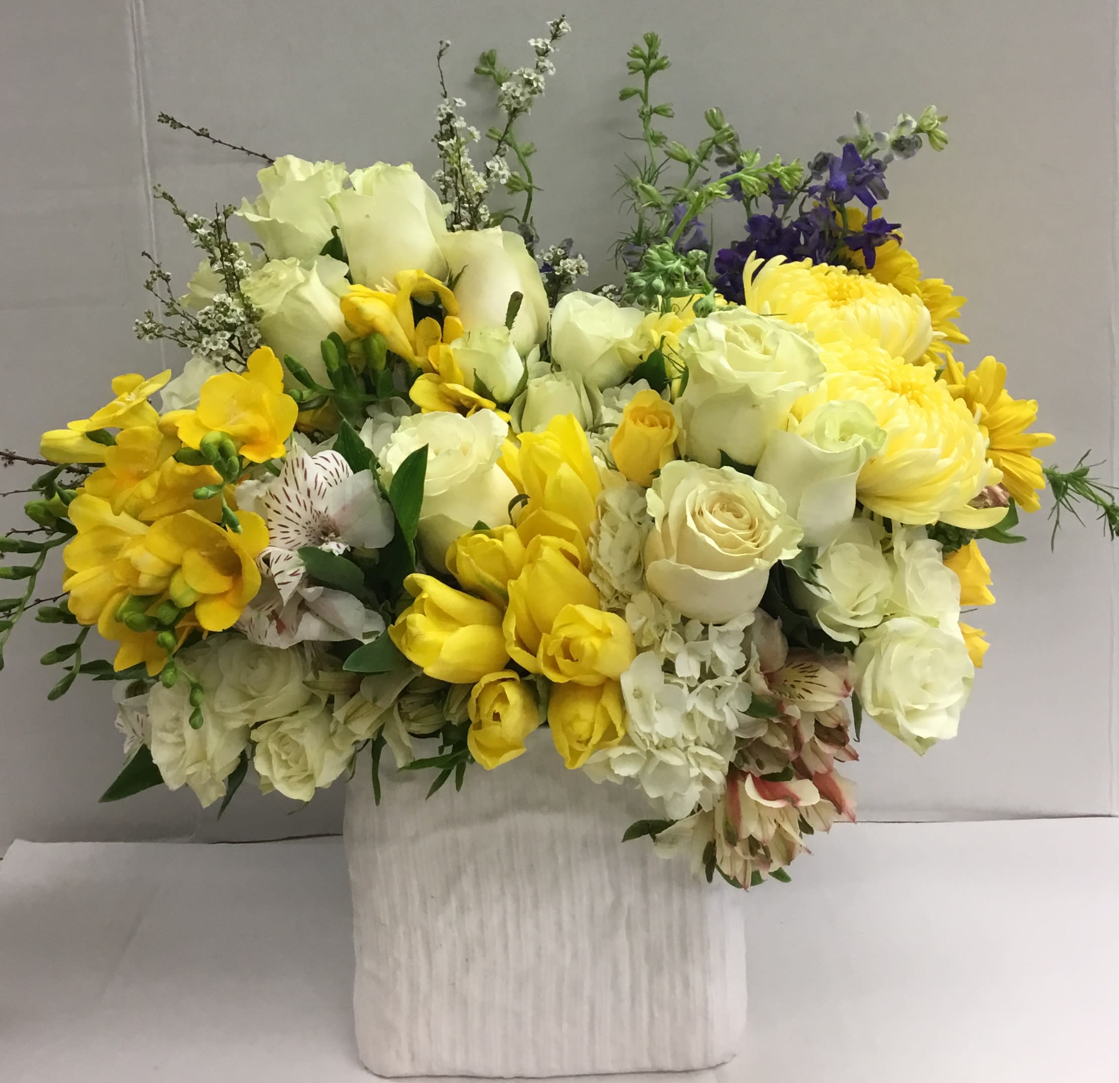 Yellow and white mixed flower arrangement in a white vase