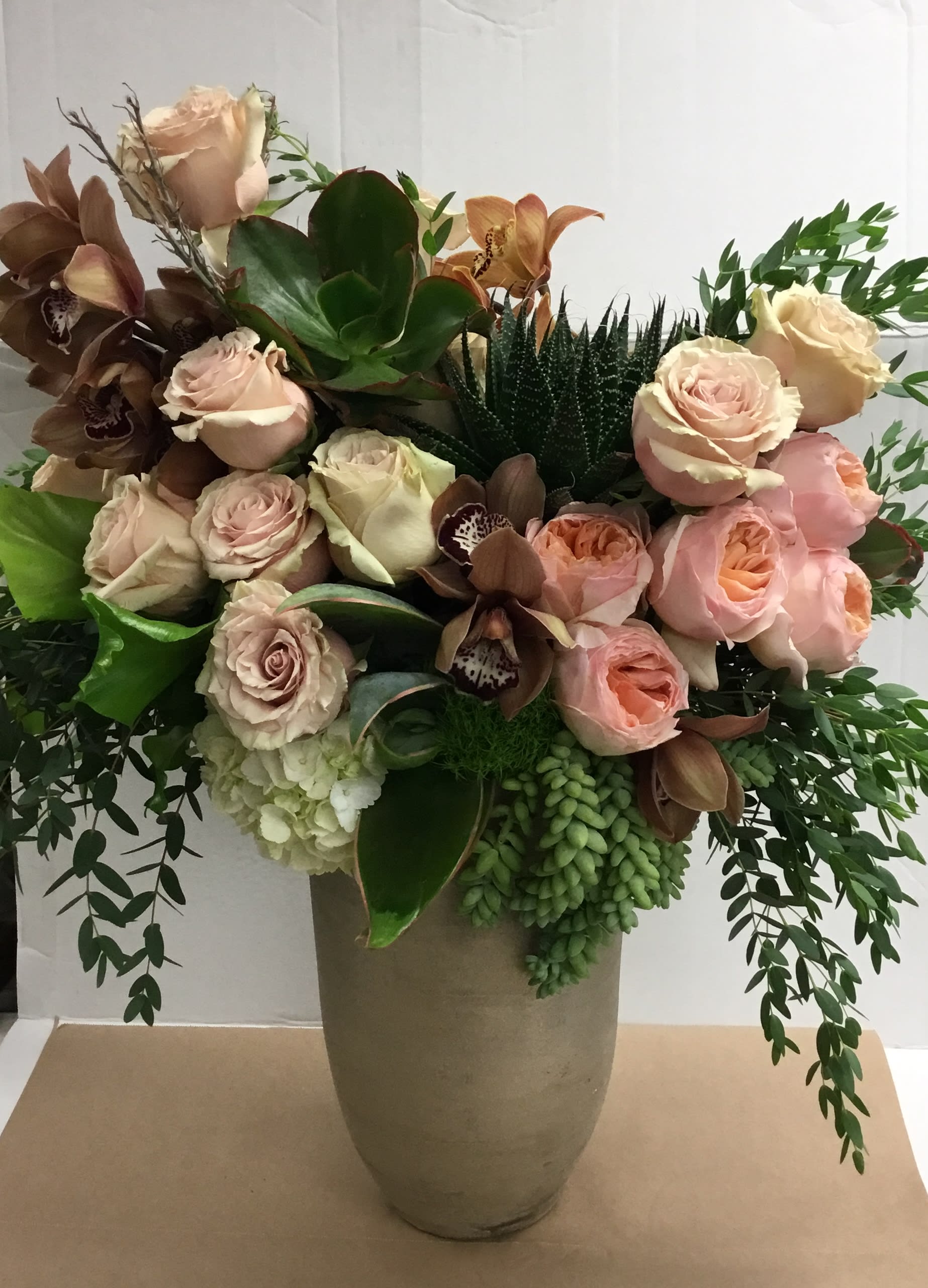 Bouquet of blush roses and orchids in a tall vase