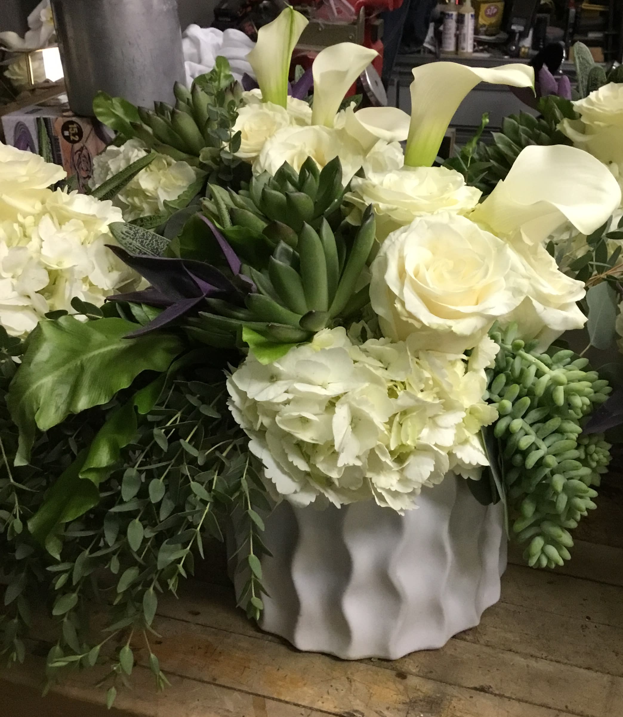 White floral arrangement with calla lilies, roses, and hydrangeas in a white vase