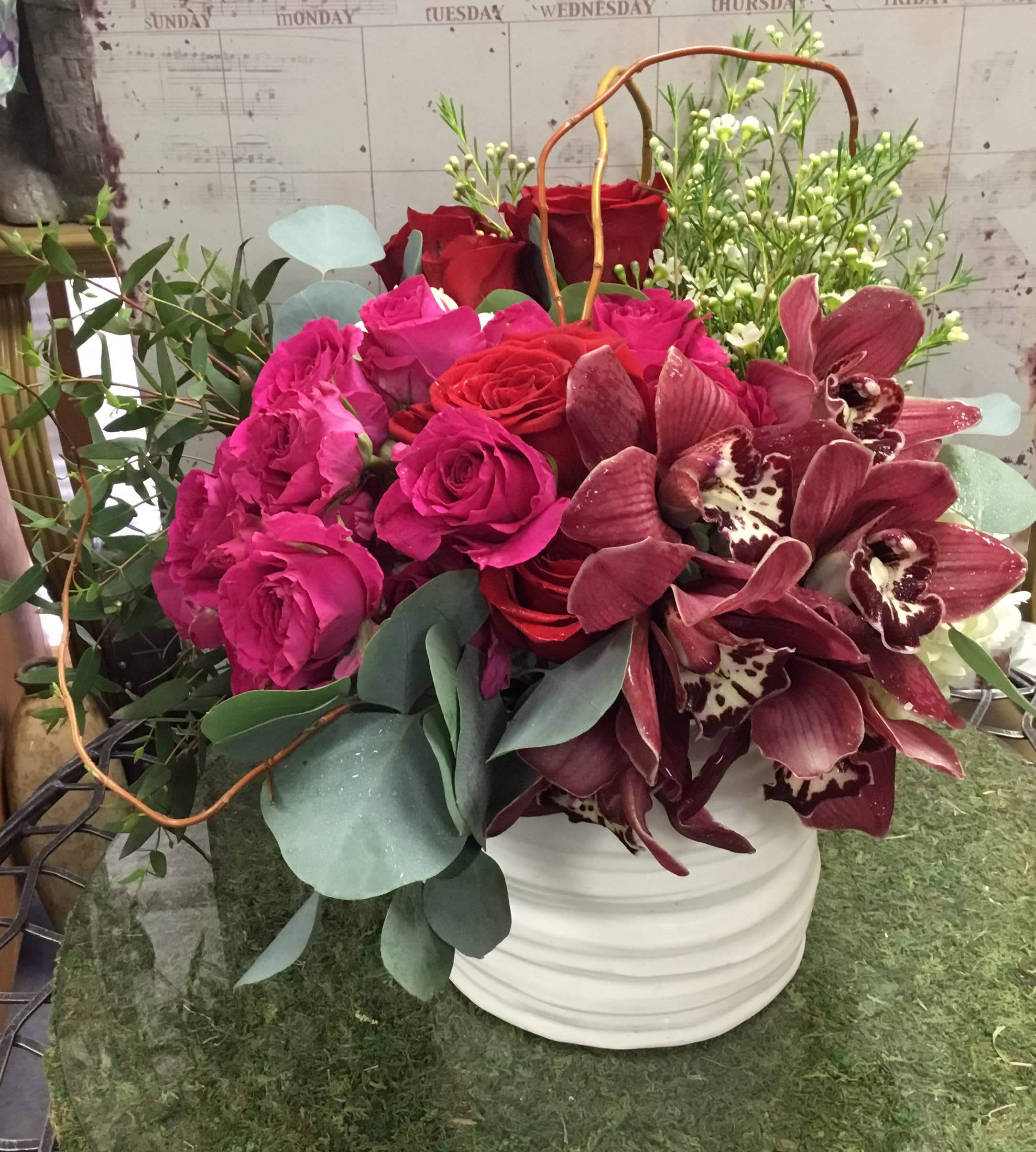 Bouquet of pink and red roses with burgundy orchids in a white vase