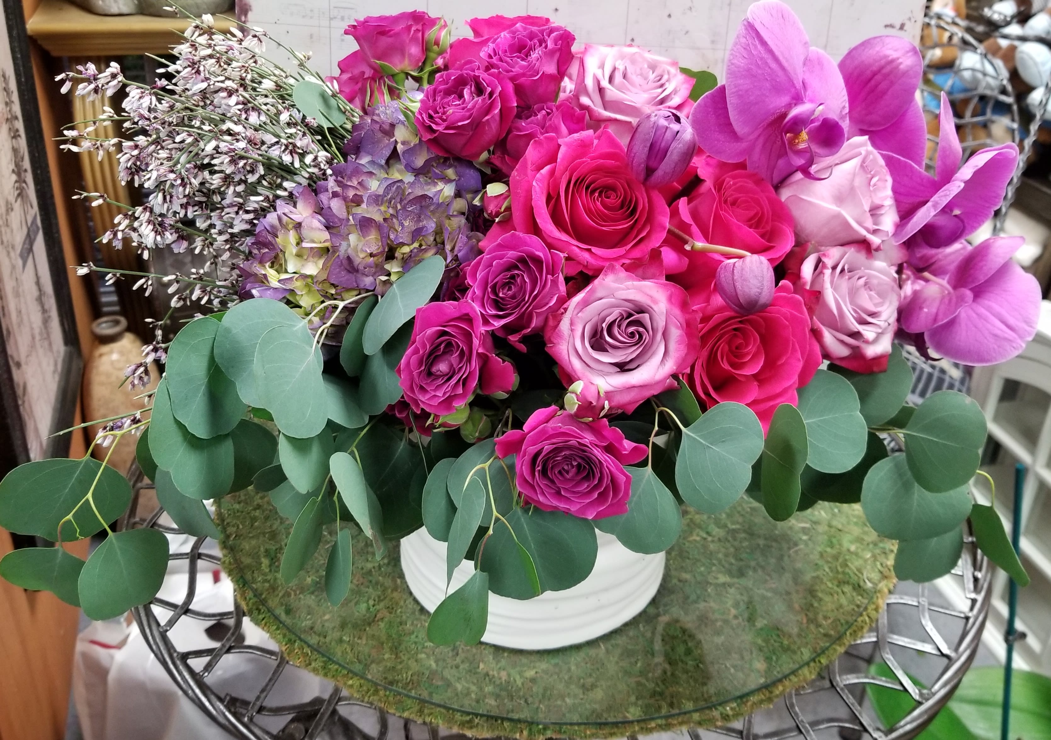 Pink and purple rose arrangement with orchids in a white vase