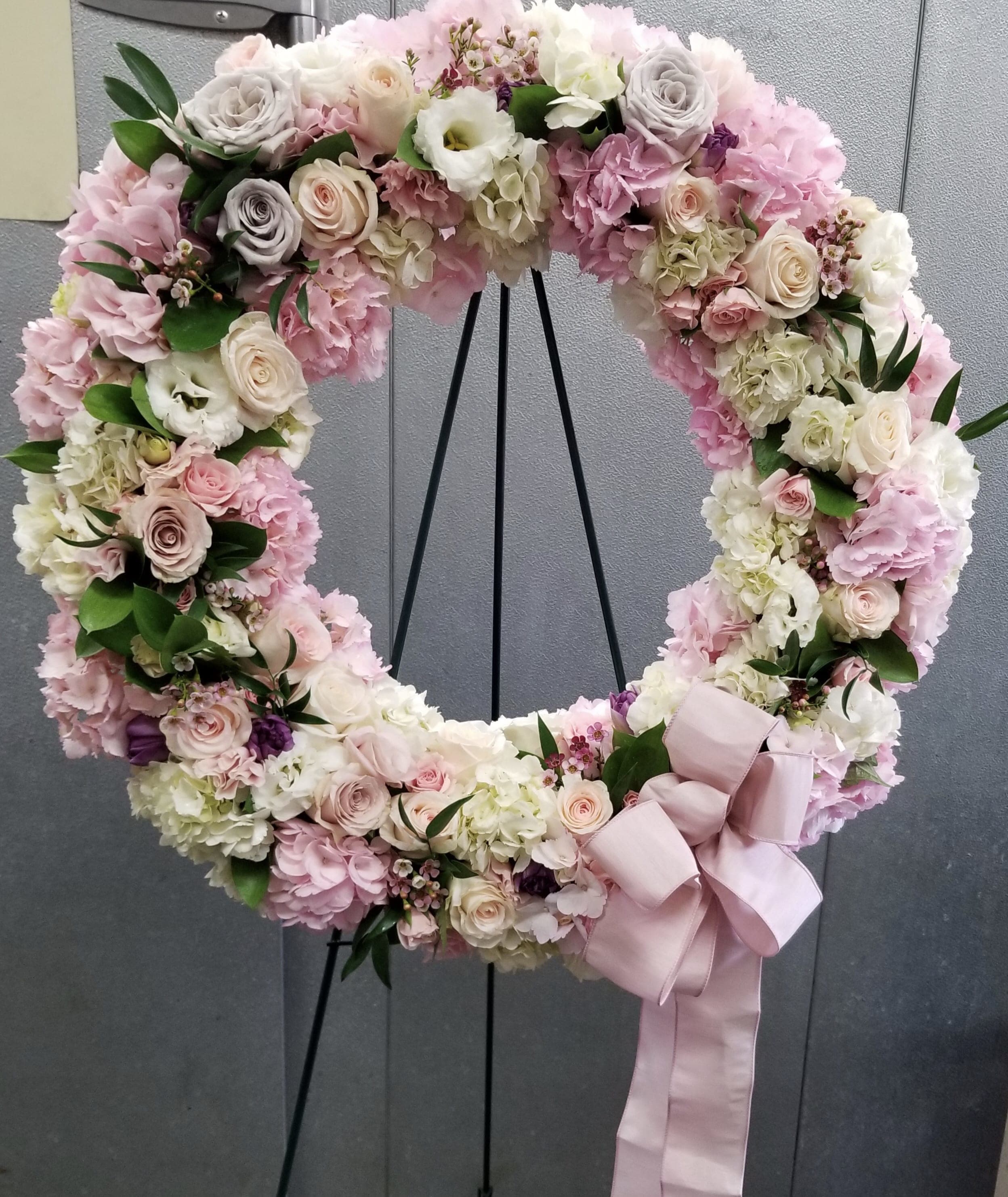 Pastel floral wreath with roses, hydrangeas, and a pink ribbon bow