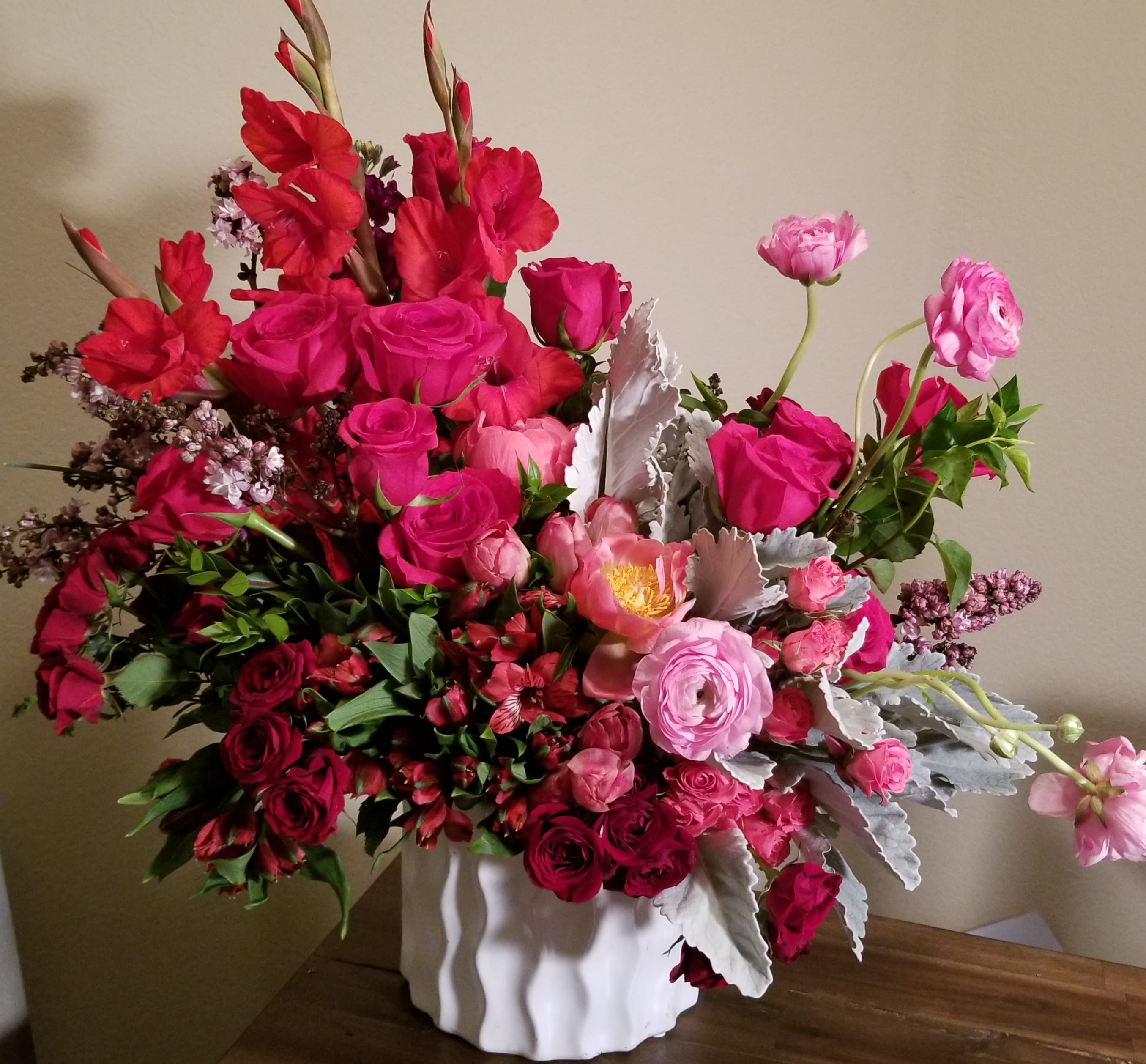 Pink and red mixed flower arrangement in a white vase