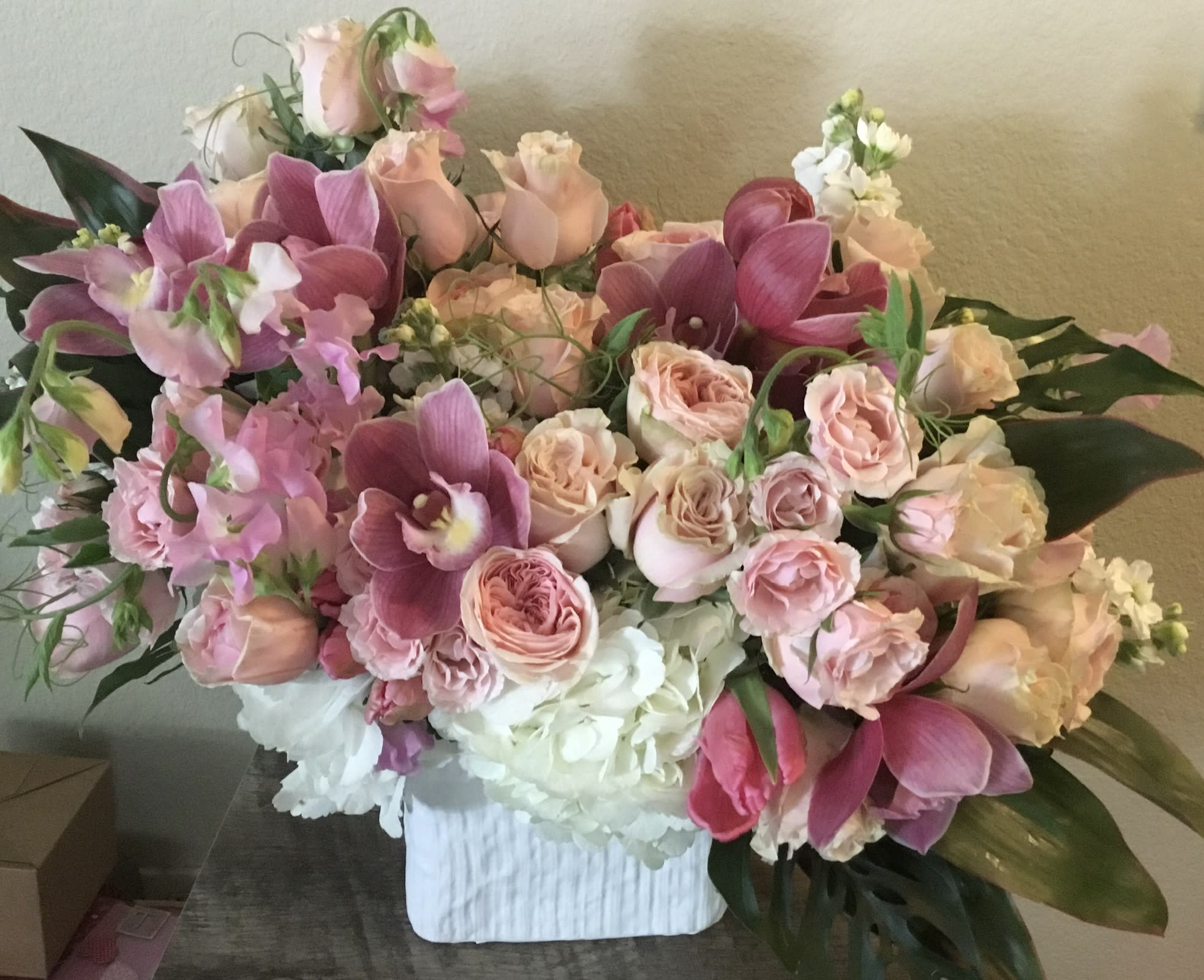 Large pink and peach floral arrangement in a white vase