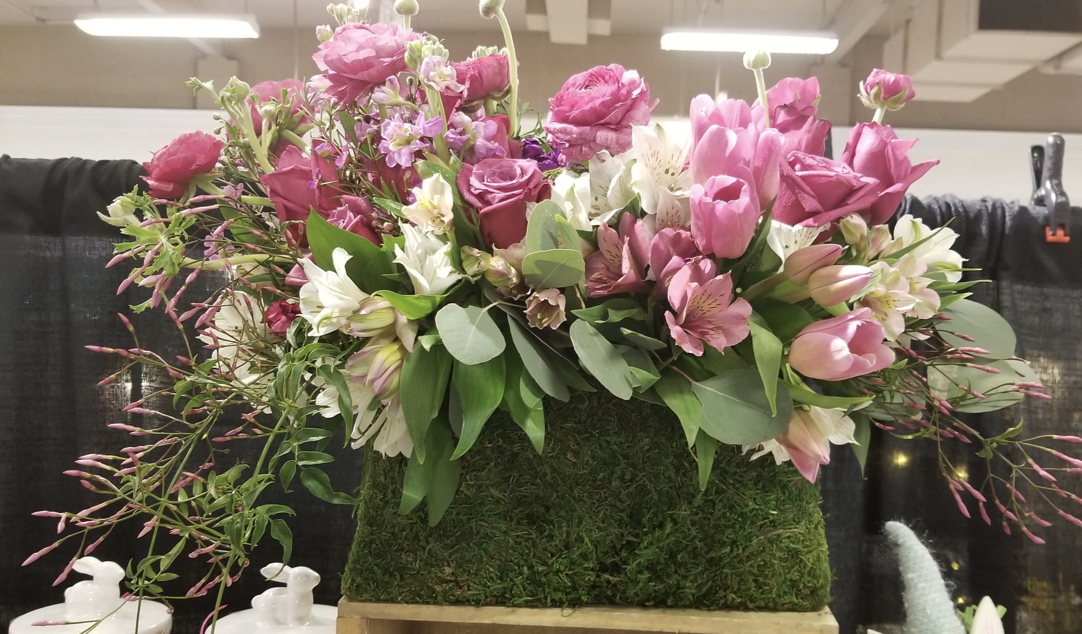 Pink and white floral arrangement in a moss-covered rectangular container