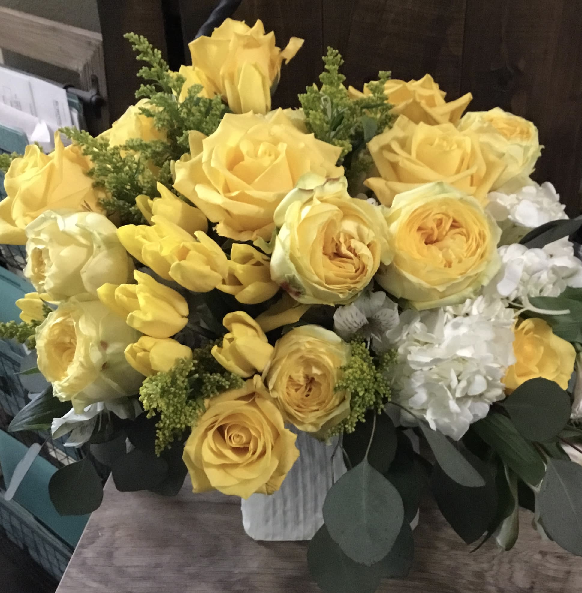 Yellow roses and tulips arranged in a white vase