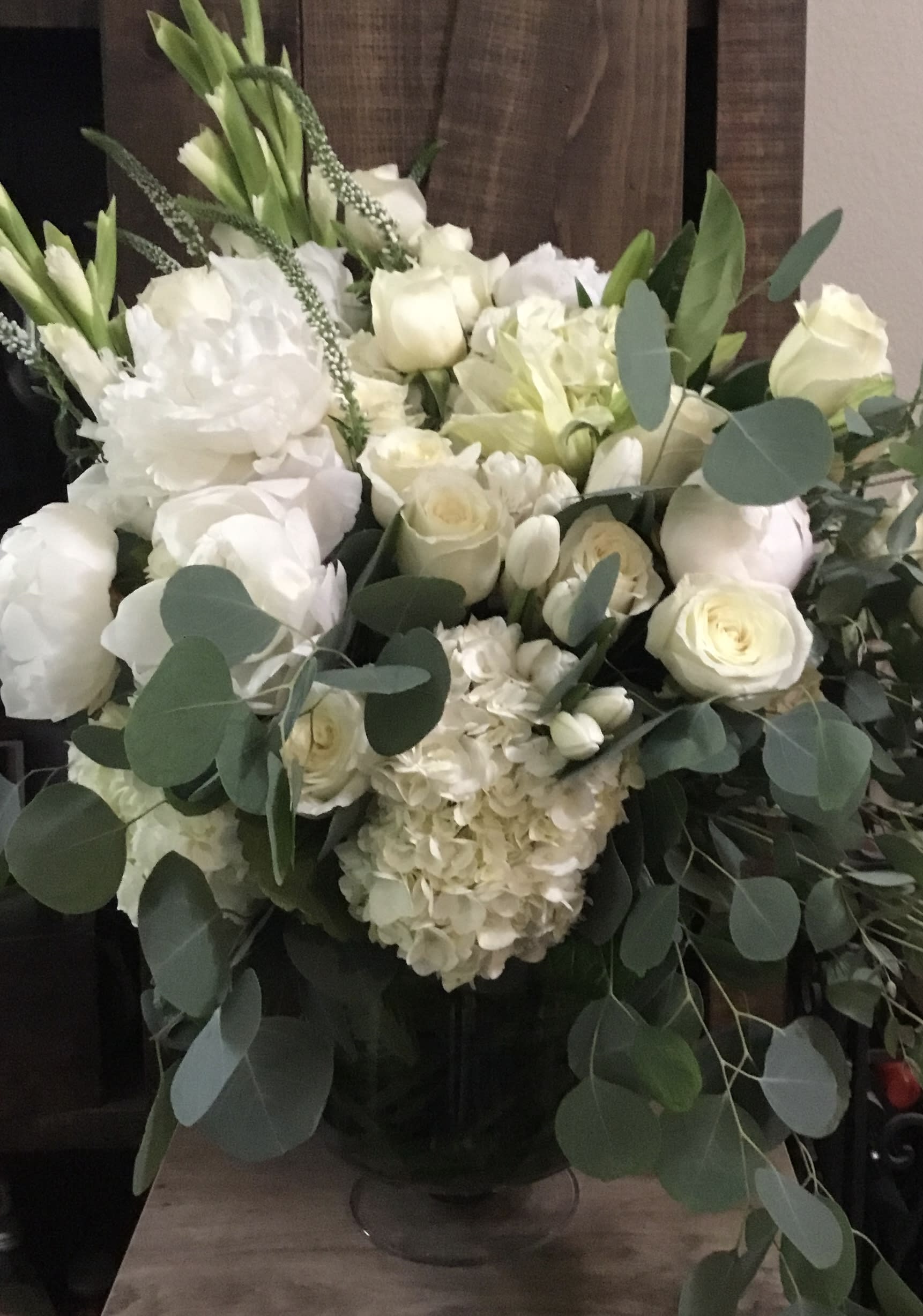 White floral arrangement with roses, hydrangeas, and greenery in a vase