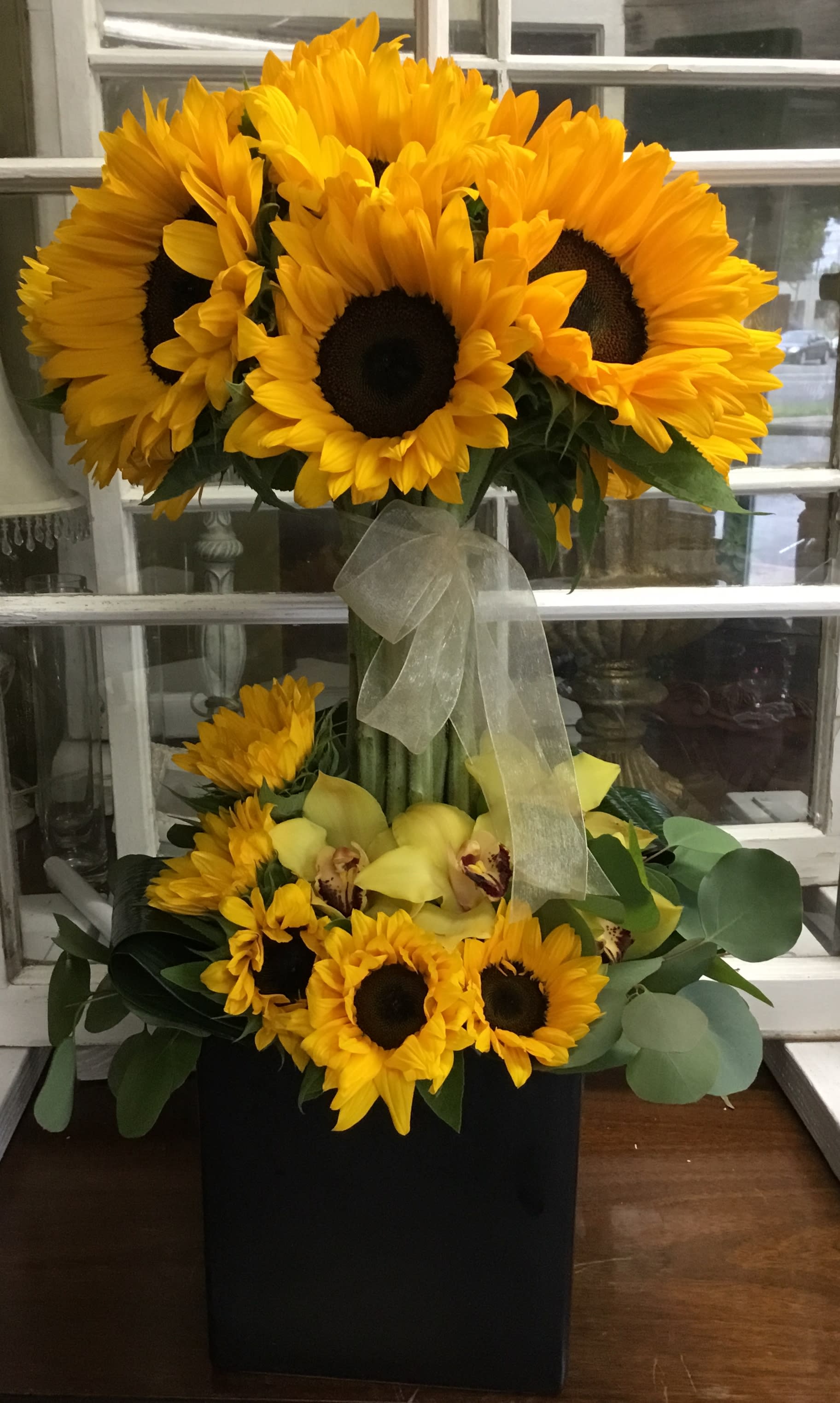 Sunflower arrangement with yellow orchids in a black box