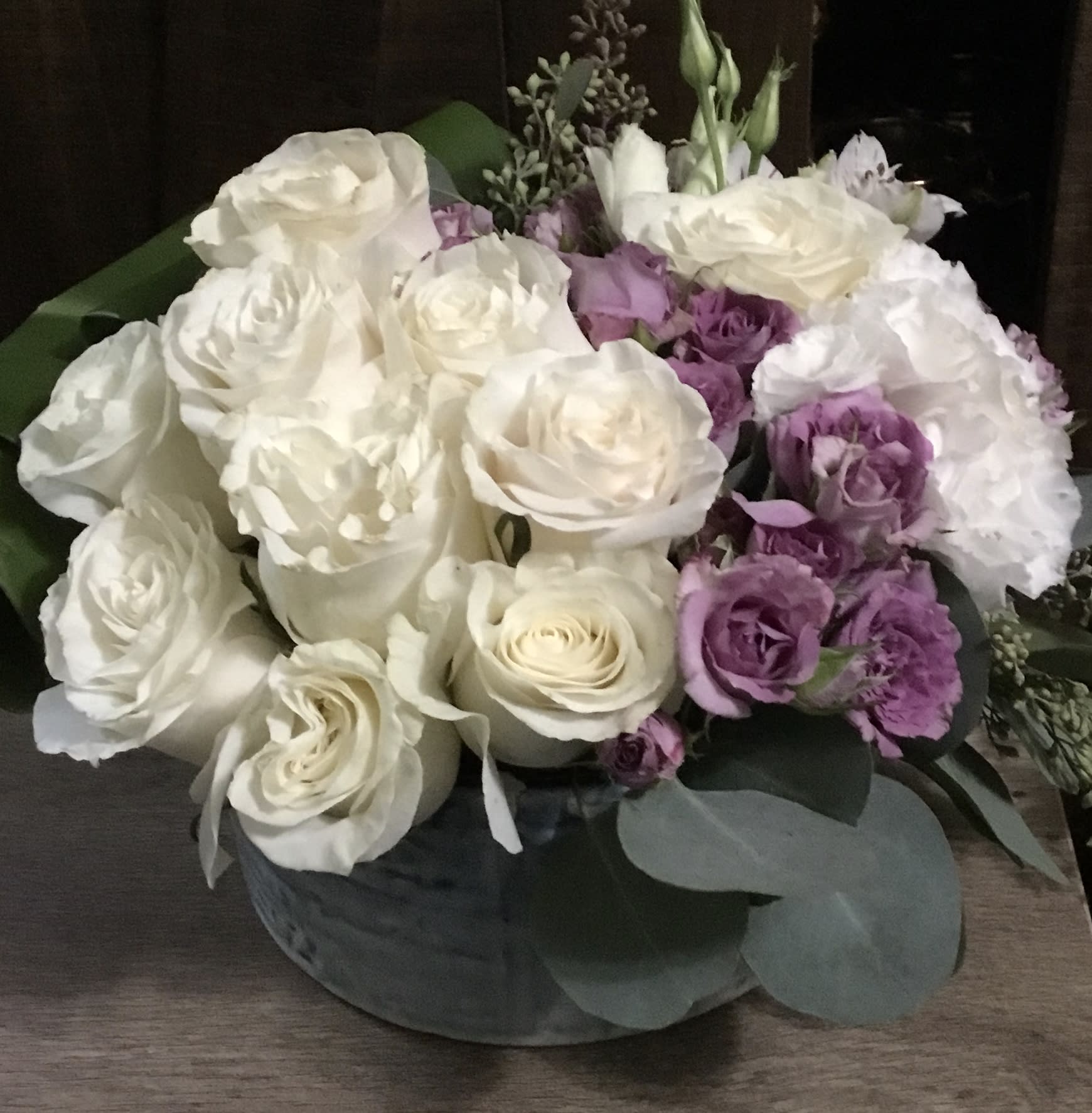 White and lavender roses arranged in a low round box